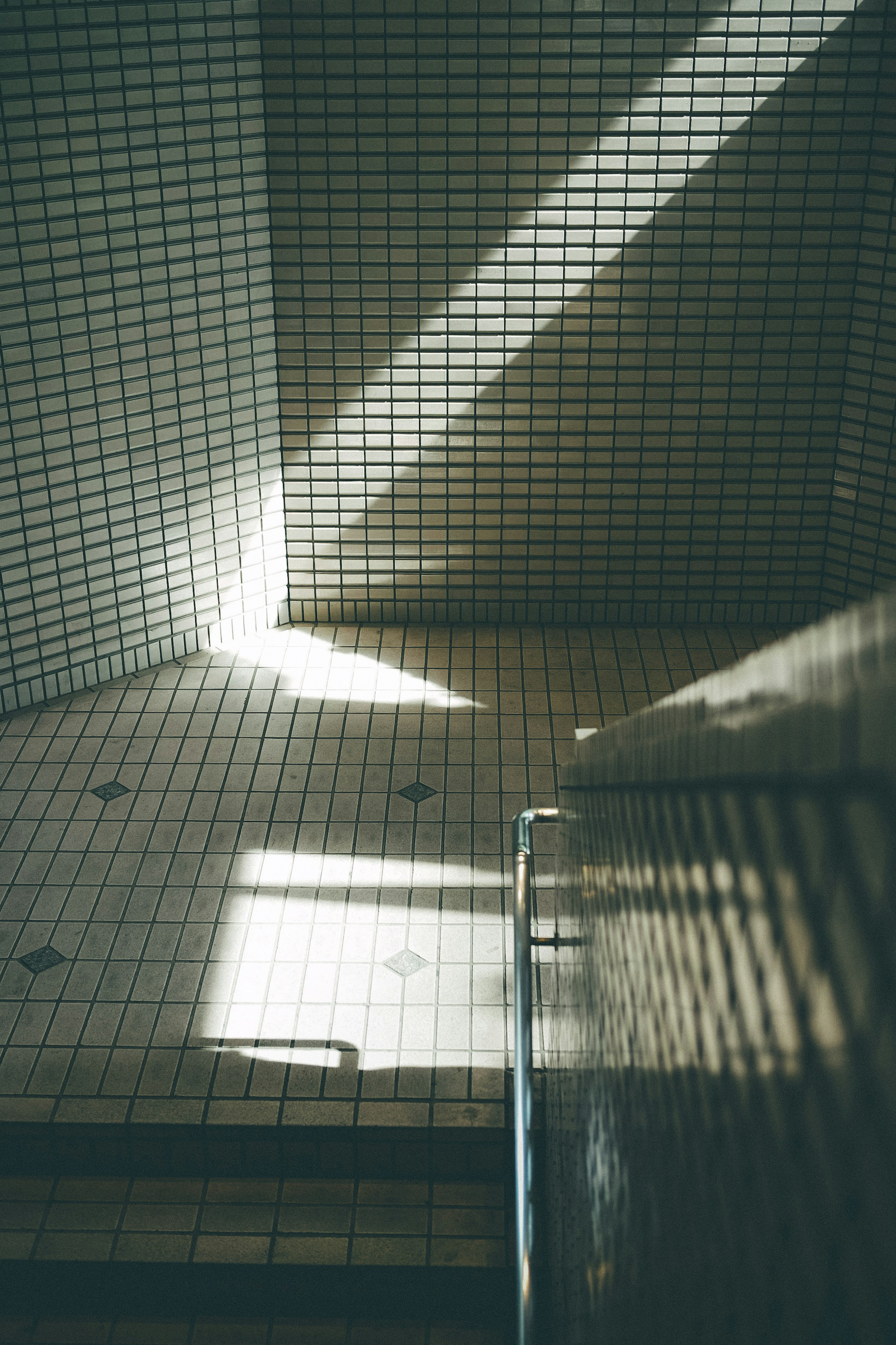 A staircase with light streaming onto the tiled floor