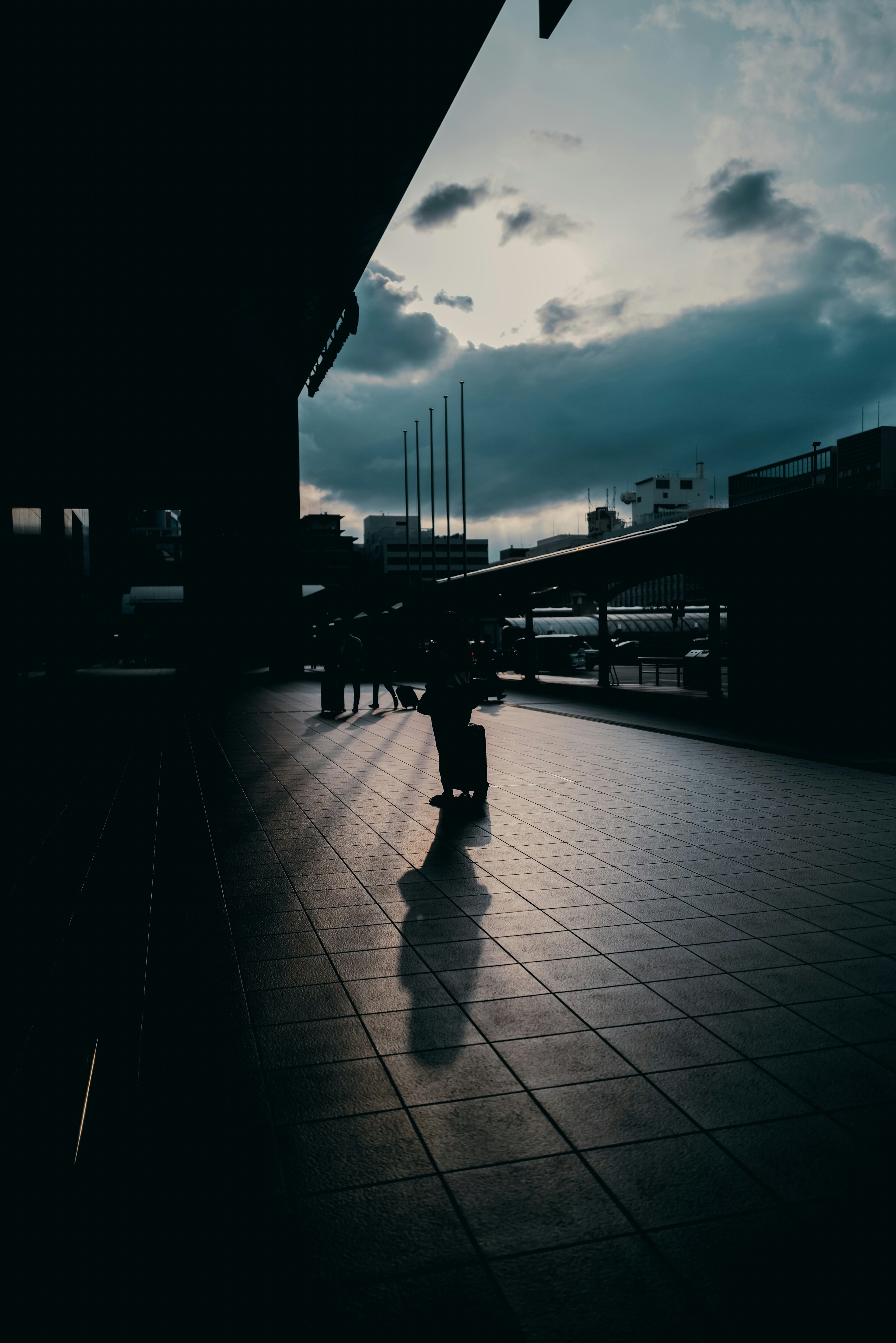 Silhouette of a person standing on a platform with a cloudy sky