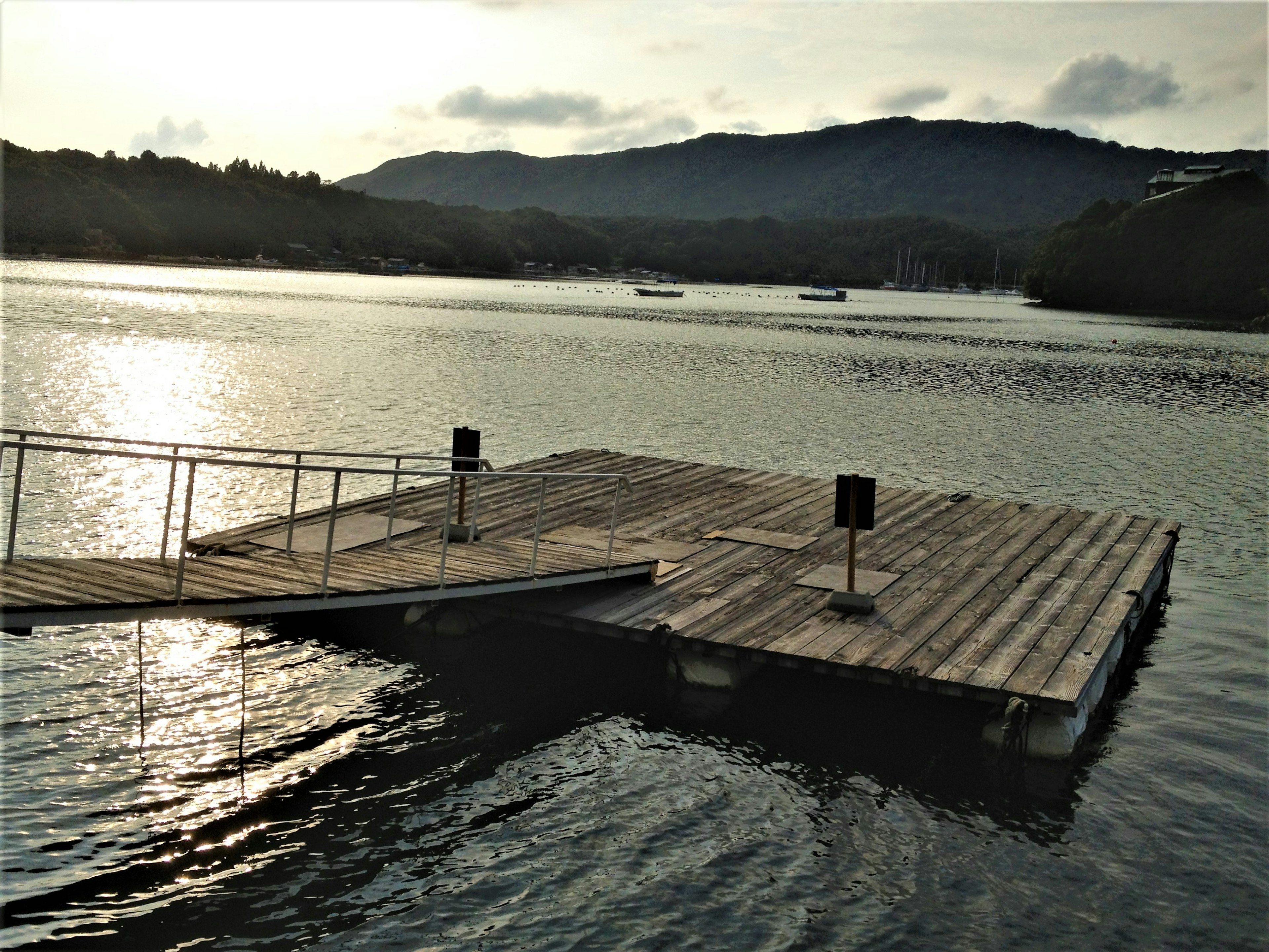 Holzsteg, der auf einem ruhigen See mit umliegenden Hügeln schwimmt