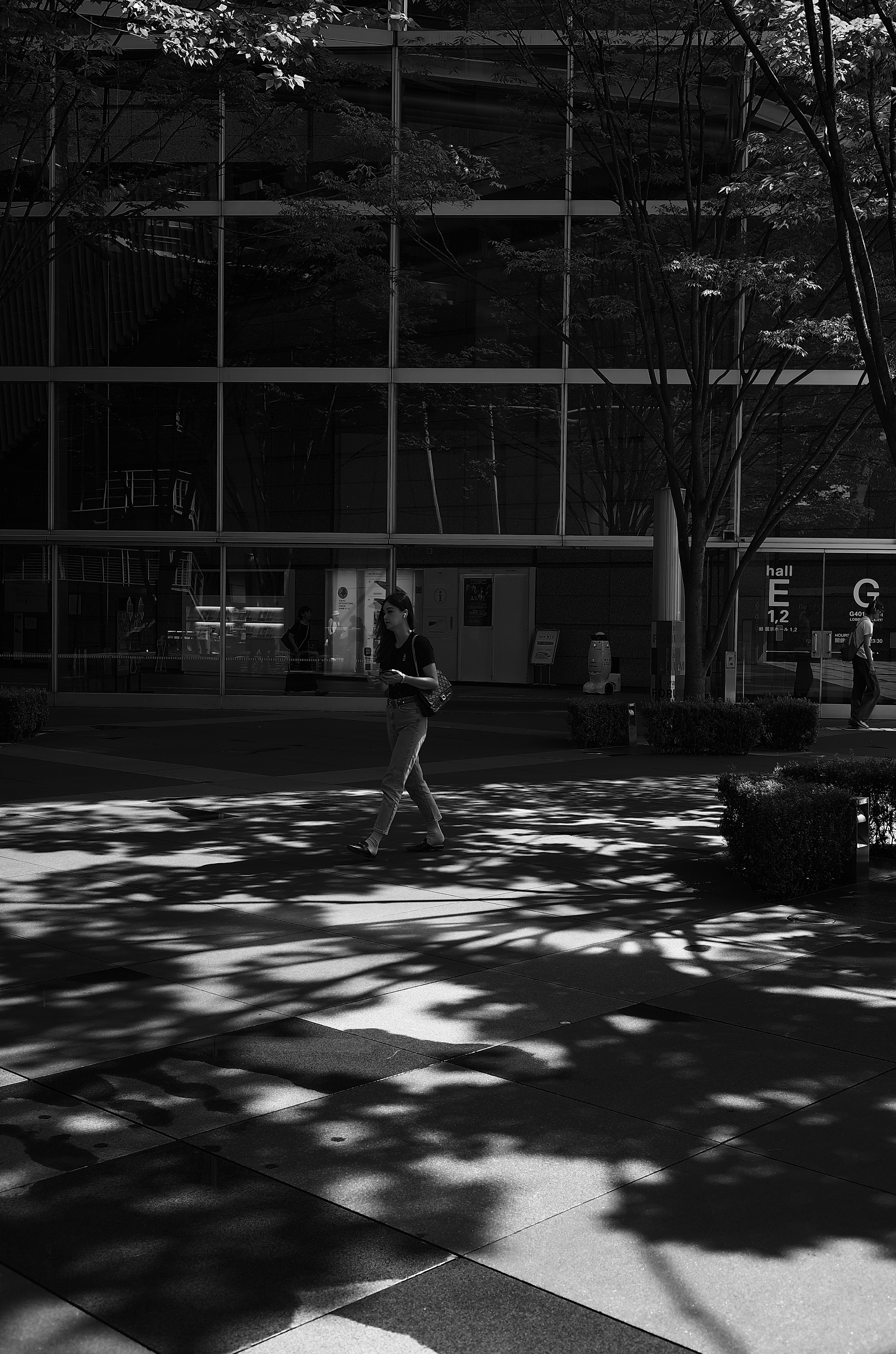 Photo en noir et blanc d'un piéton marchant à travers des ombres