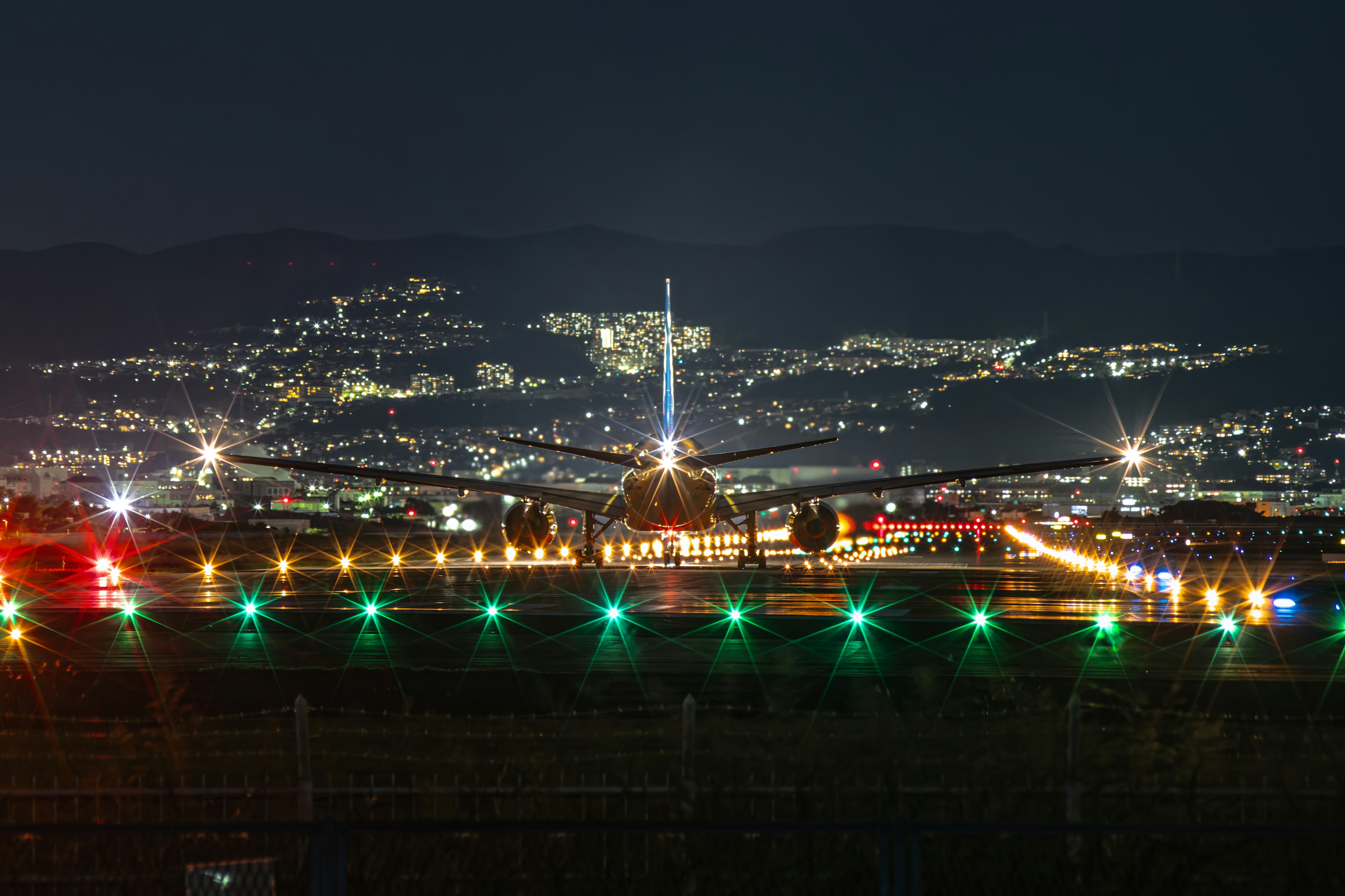 An airplane landing at night with a beautiful city skyline in the background