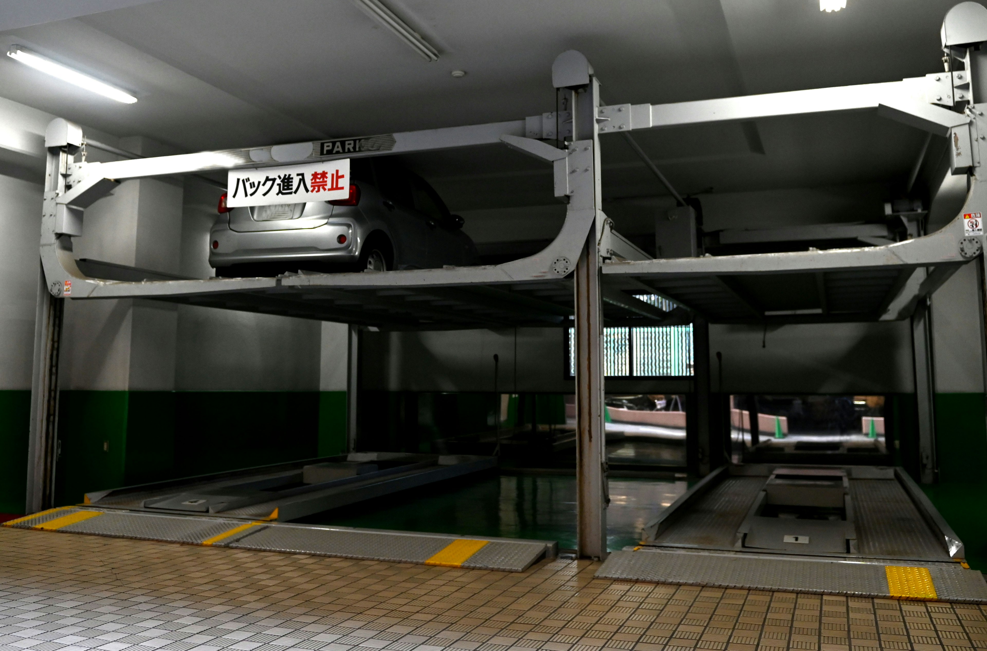 Interior of a two-level parking garage with a vehicle parked on the upper level