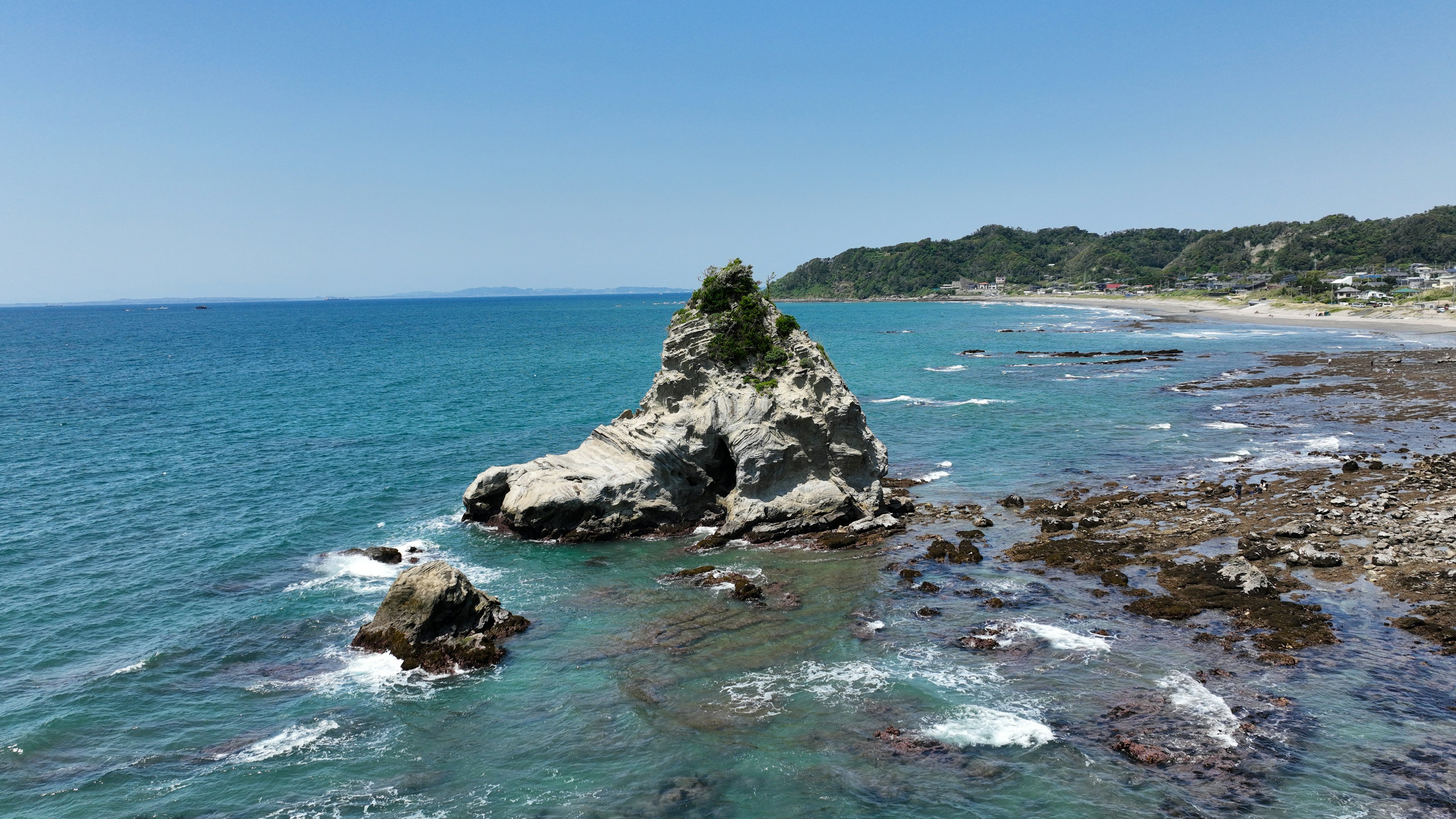 Coastal landscape featuring a rocky outcrop and clear blue ocean