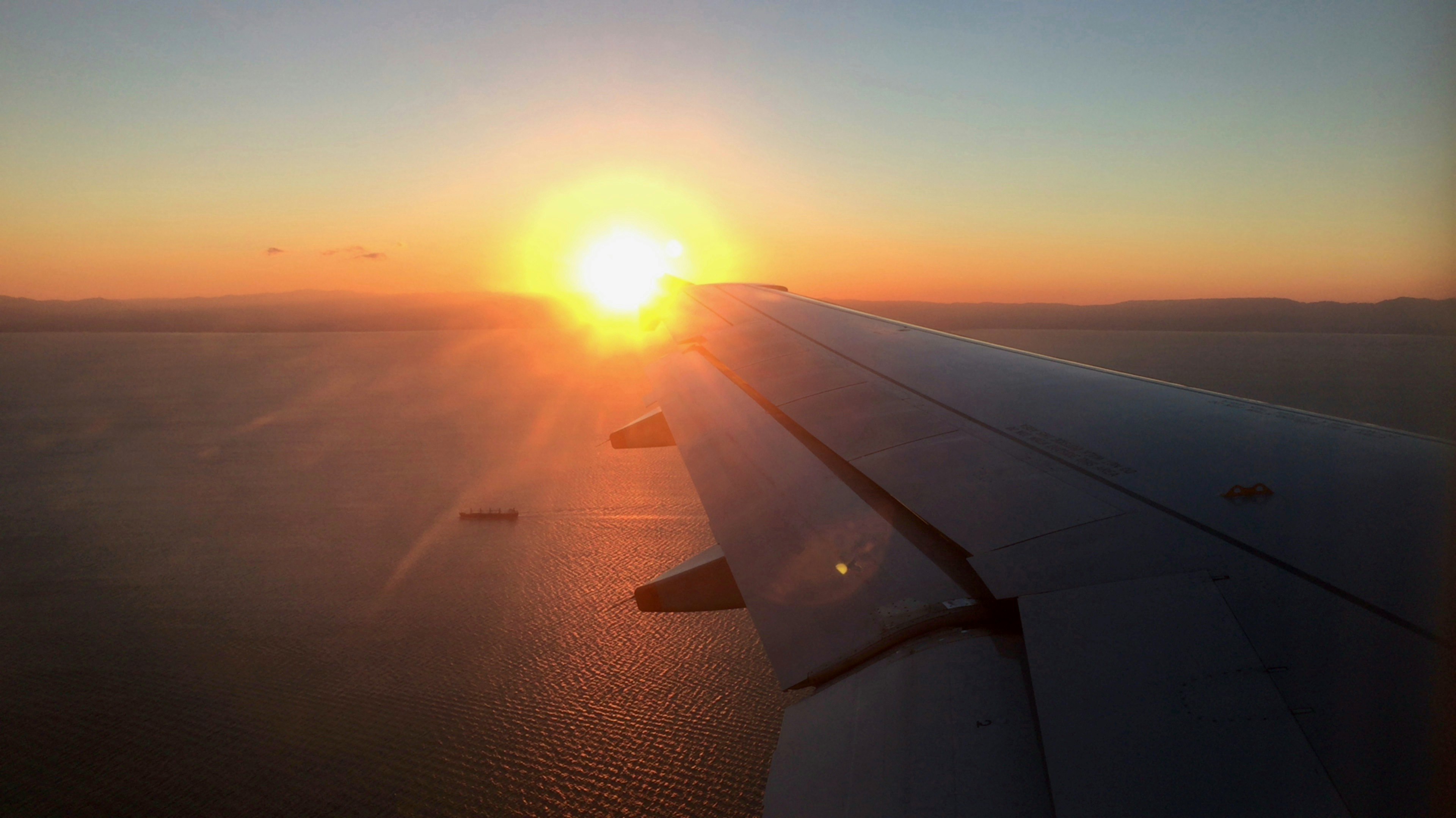 Vista del tramonto dall'ala di un aereo sopra l'oceano