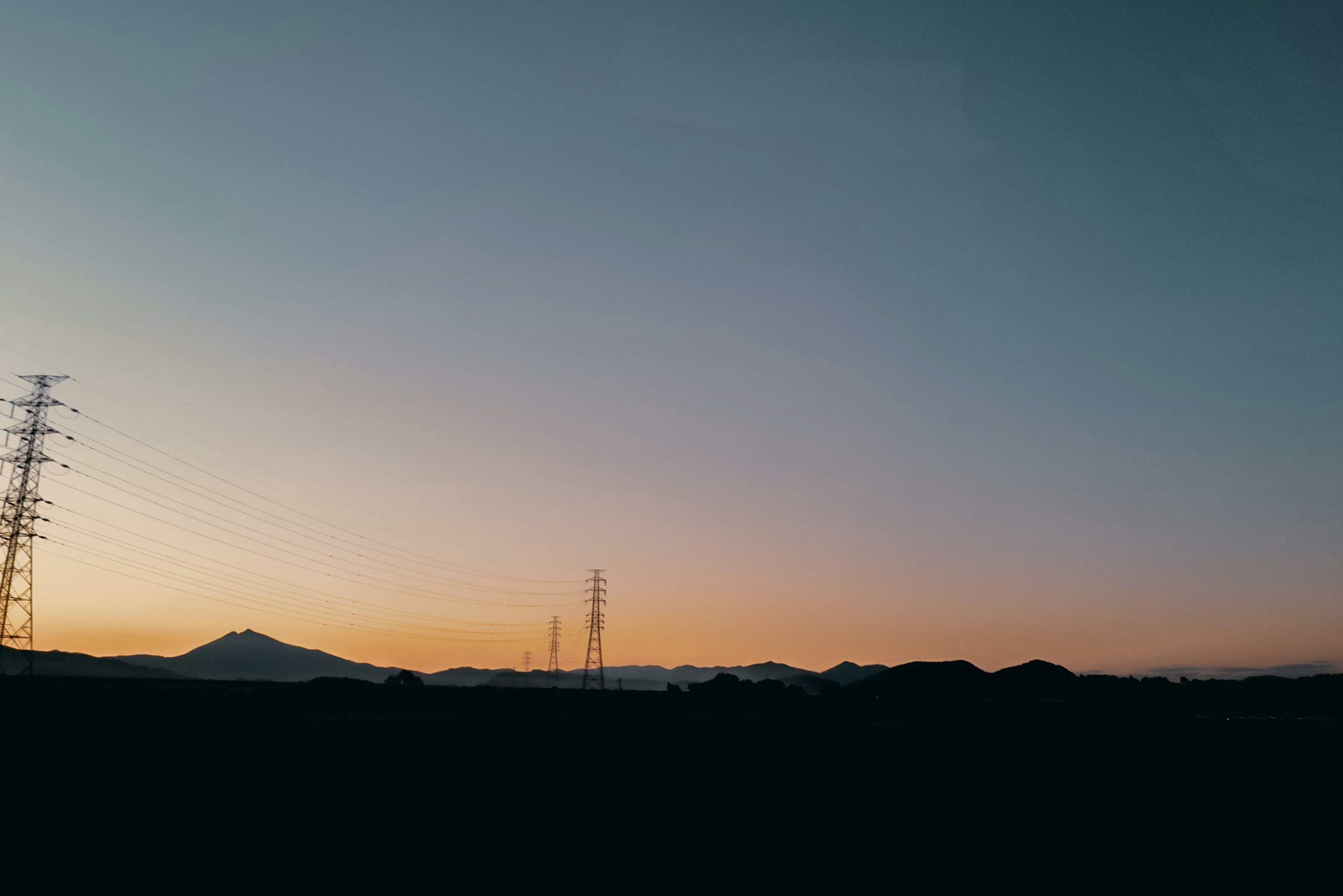 Paysage avec ciel de coucher de soleil et lignes électriques en silhouette