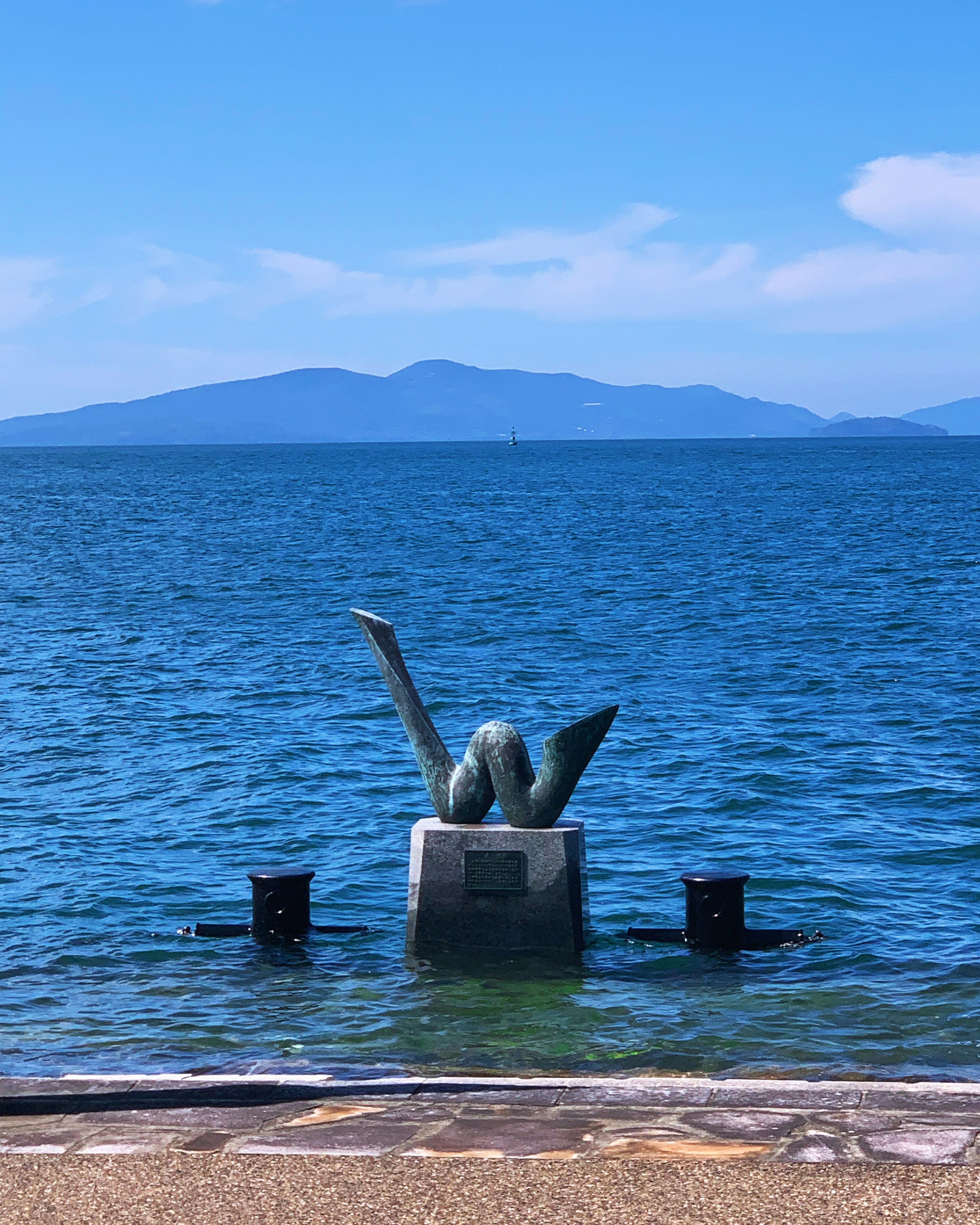 Eine malerische Aussicht mit einer Skulptur, die aus blauem Wasser ragt