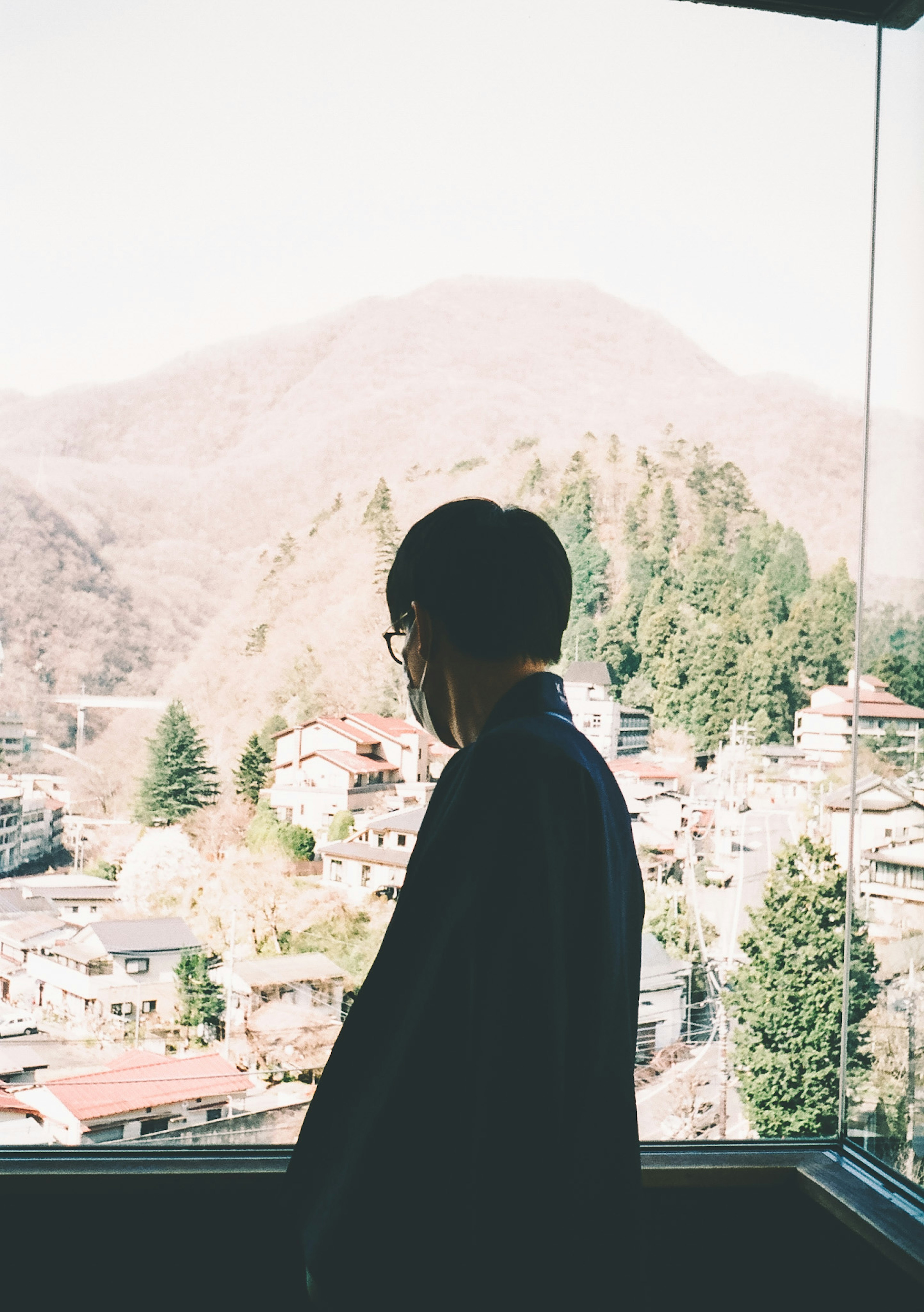 Silhouette eines Mannes, der an einem Fenster mit Berglandschaft steht