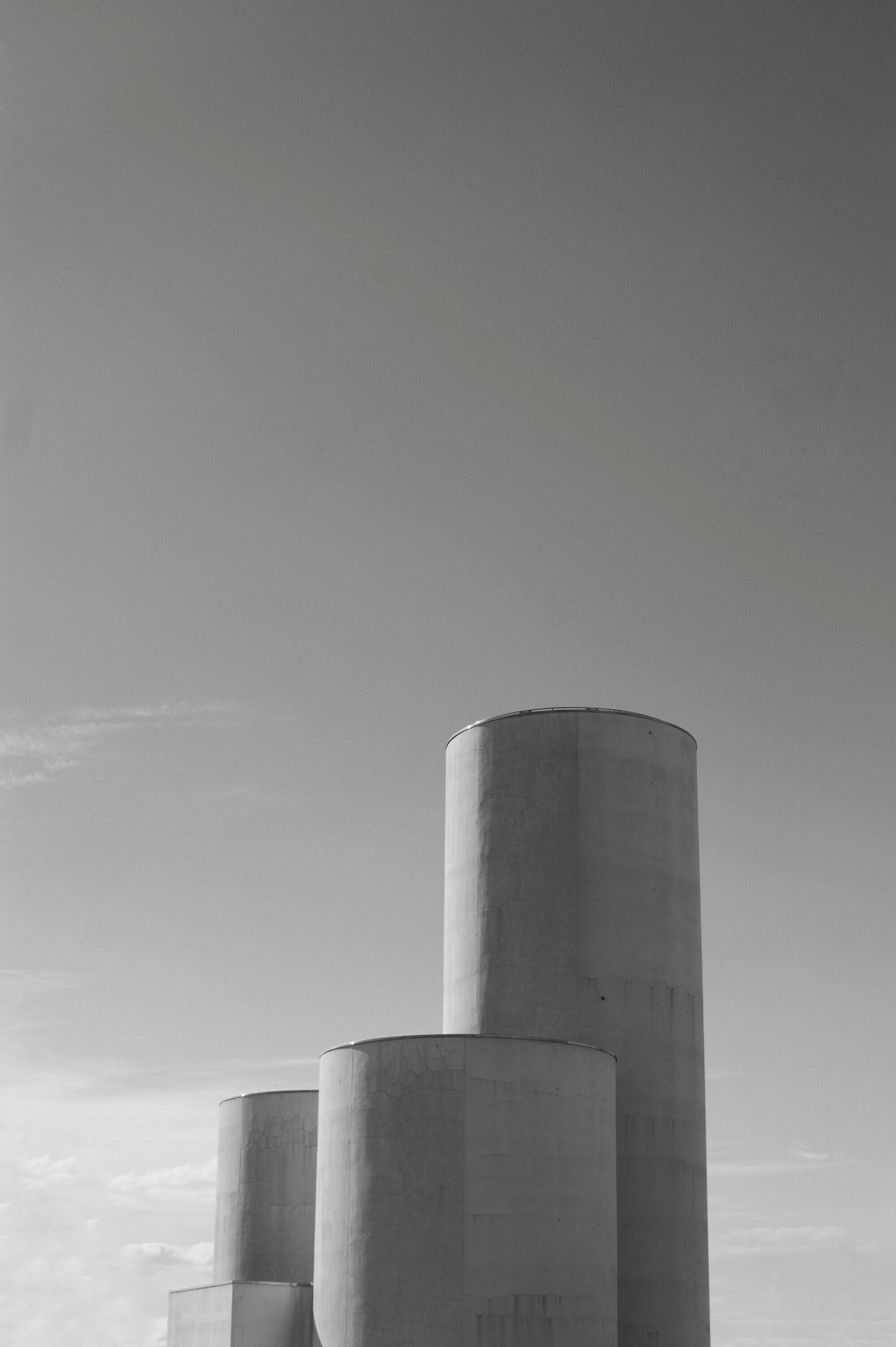 Monochrome image of architectural silhouettes featuring large cylindrical and trapezoidal structures