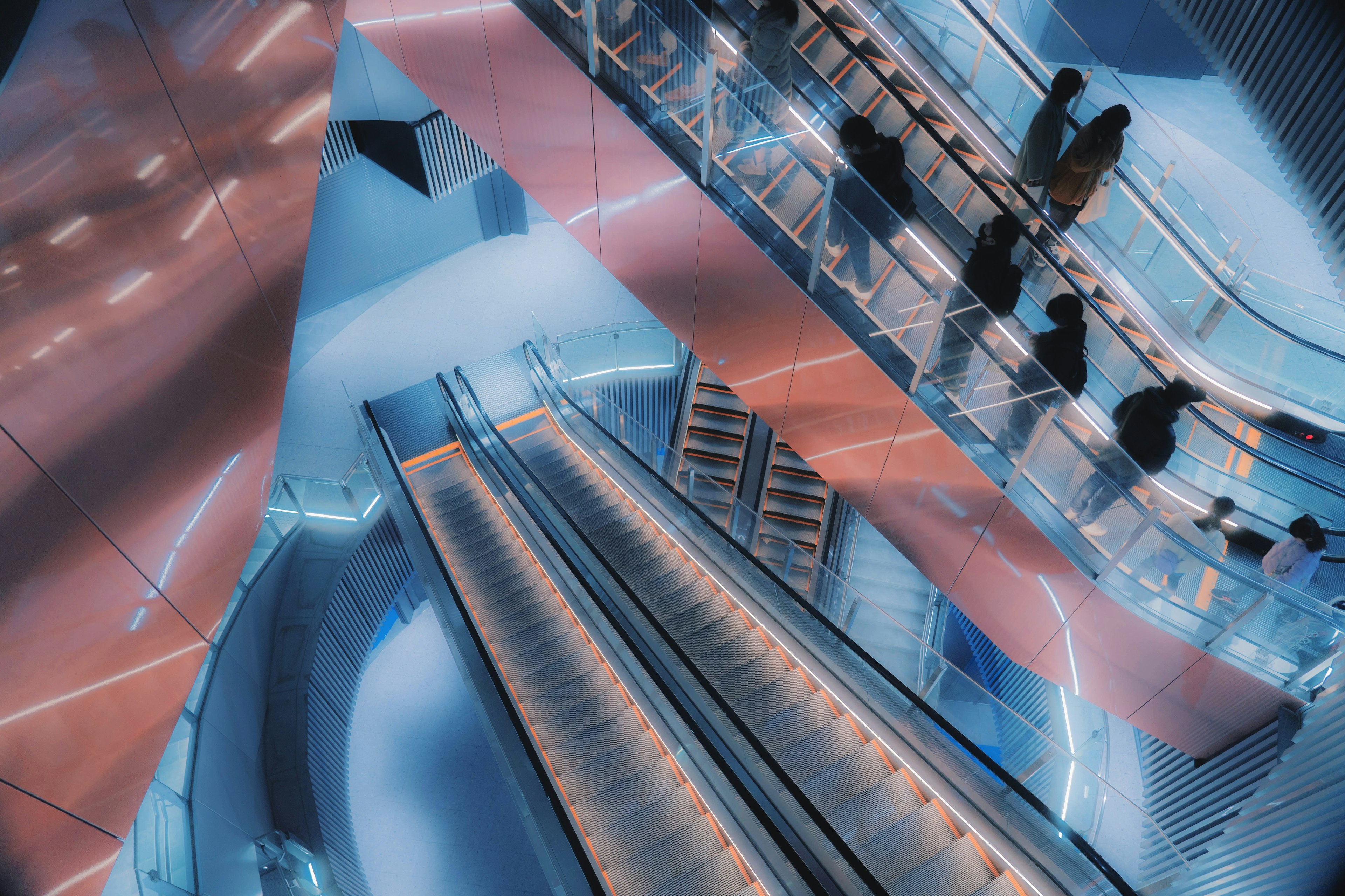 Futuristic interior with escalators and silhouettes of people