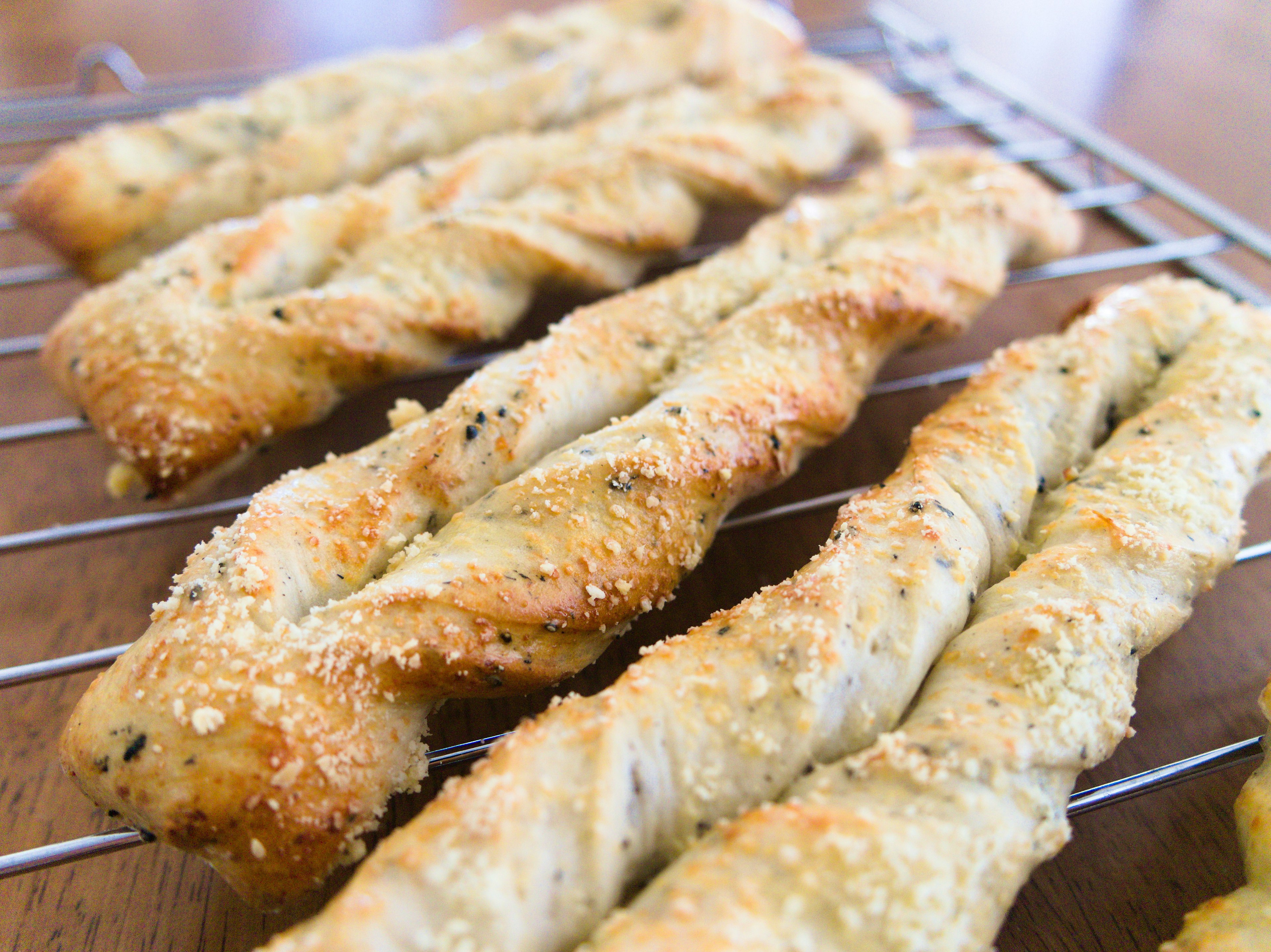 Freshly baked twisted breadsticks placed on a cooling rack