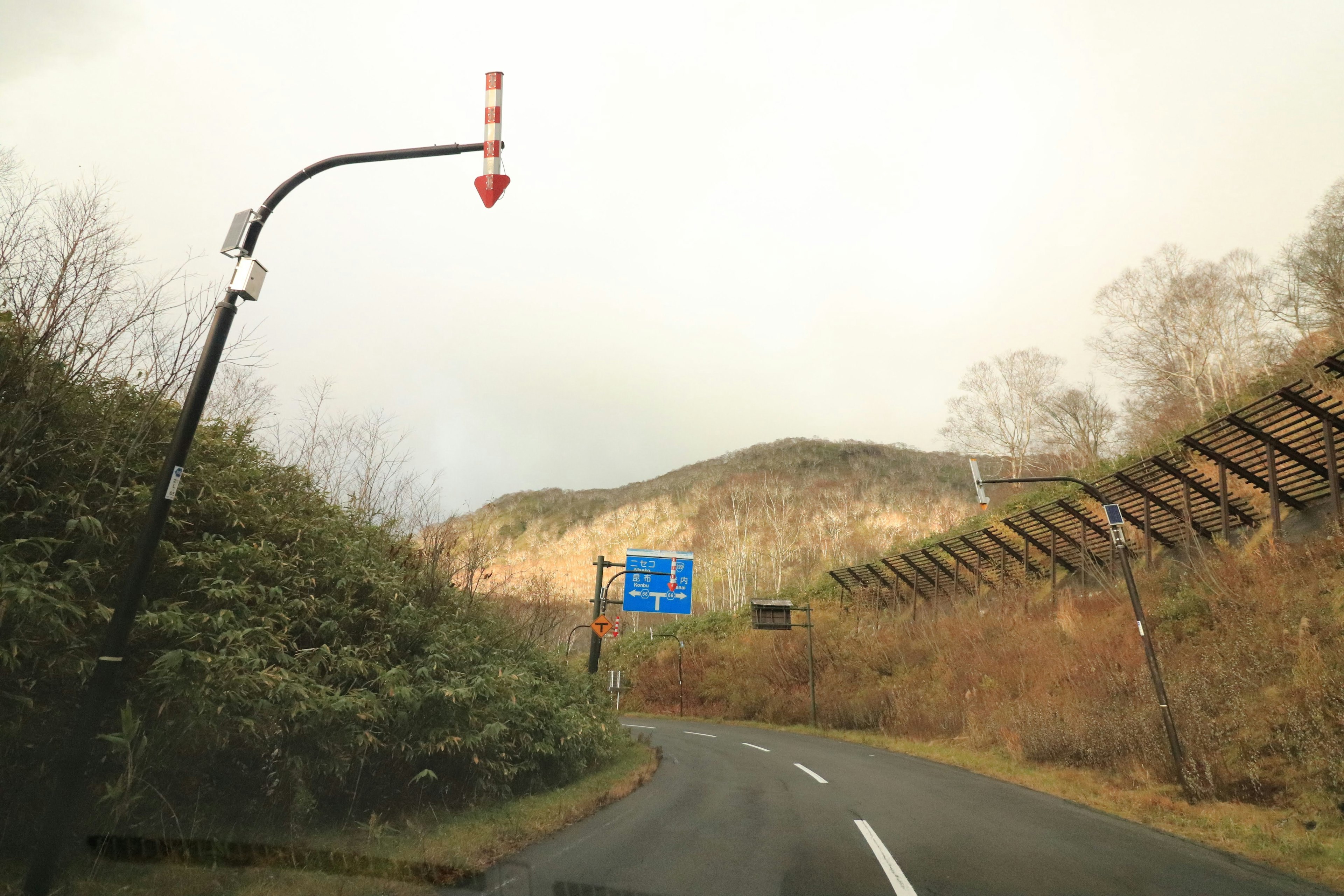 Verkehrsschild, das eine Kurve mit Berglandschaft anzeigt