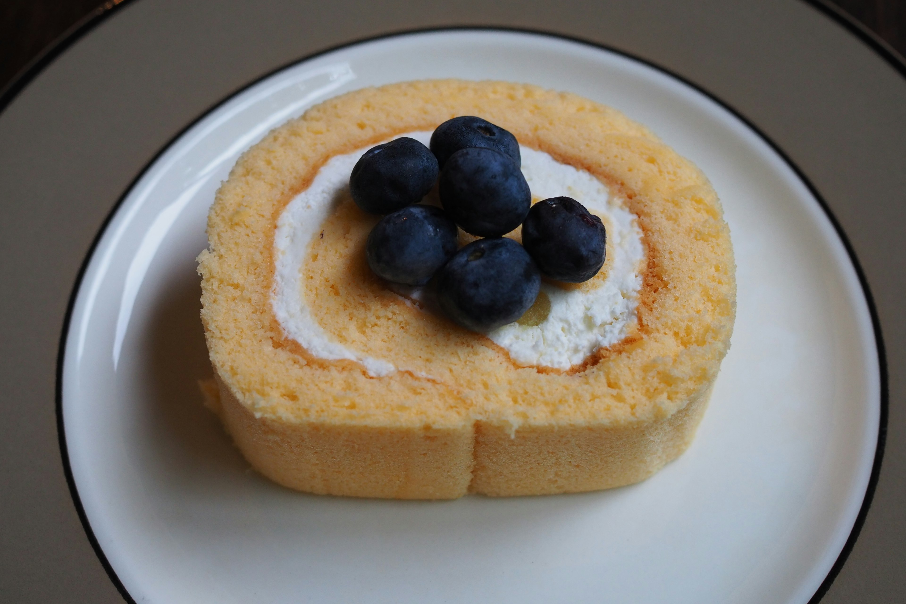 Slice of roll cake topped with blueberries