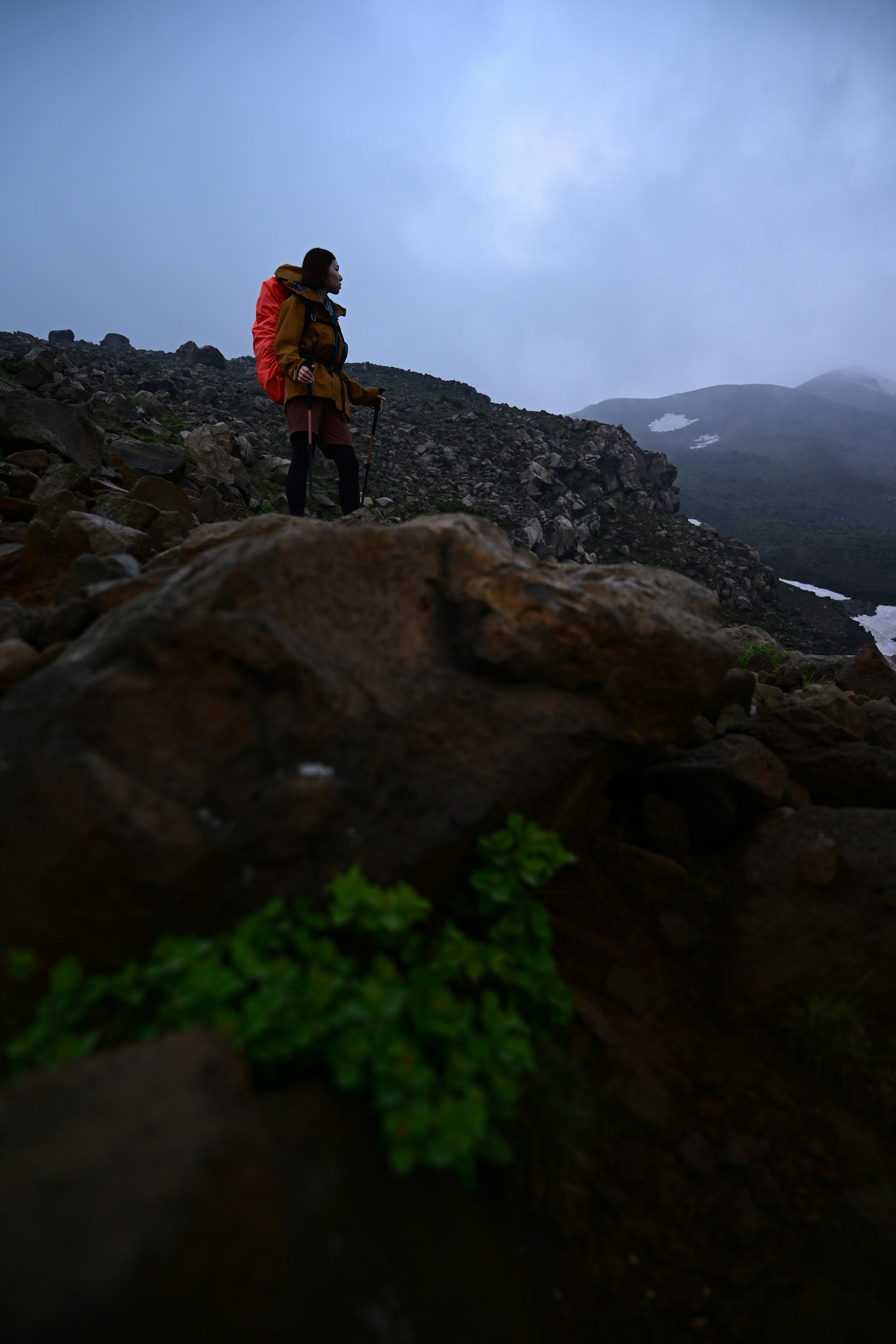 Mountaineer standing on a rock in foggy conditions with mountains in the background