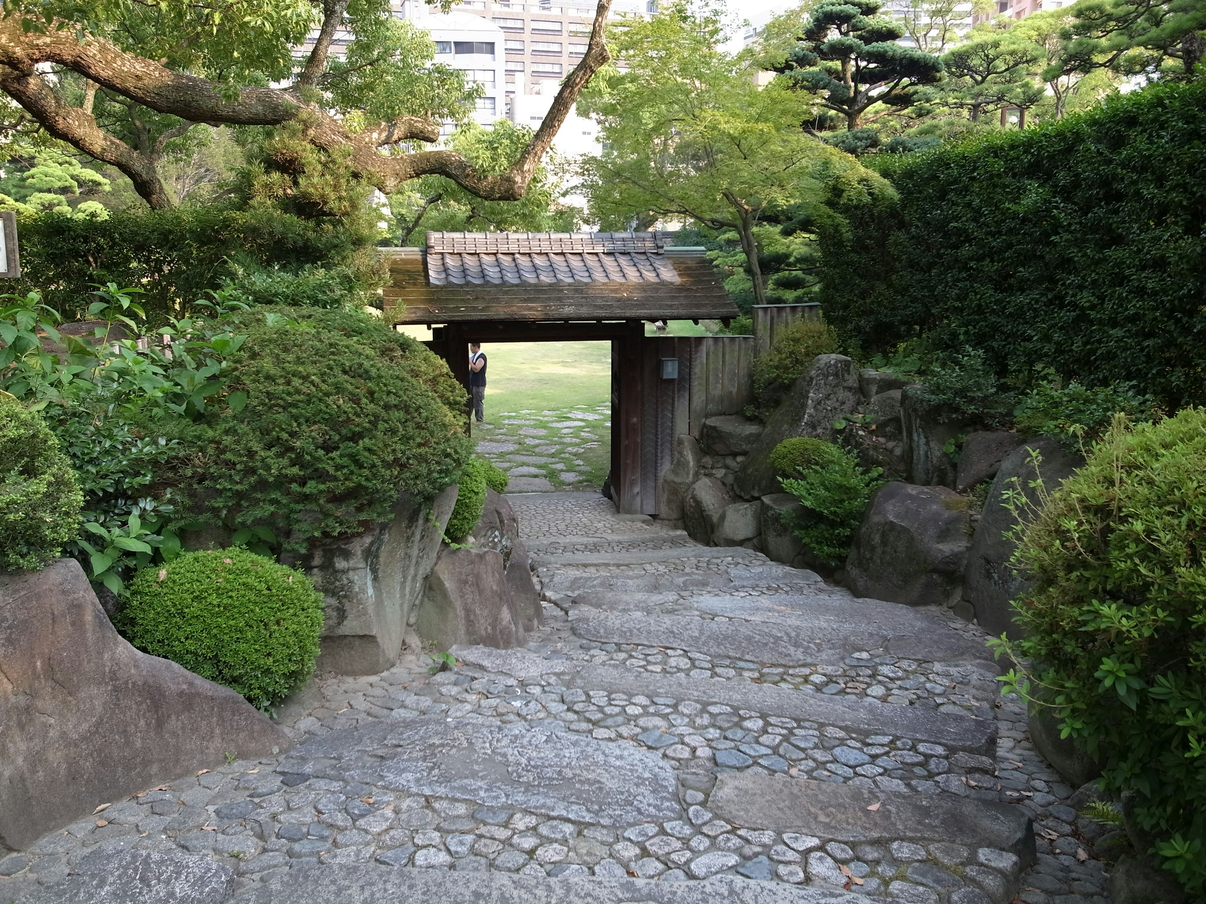 Stone path leading to a lush garden entrance with greenery