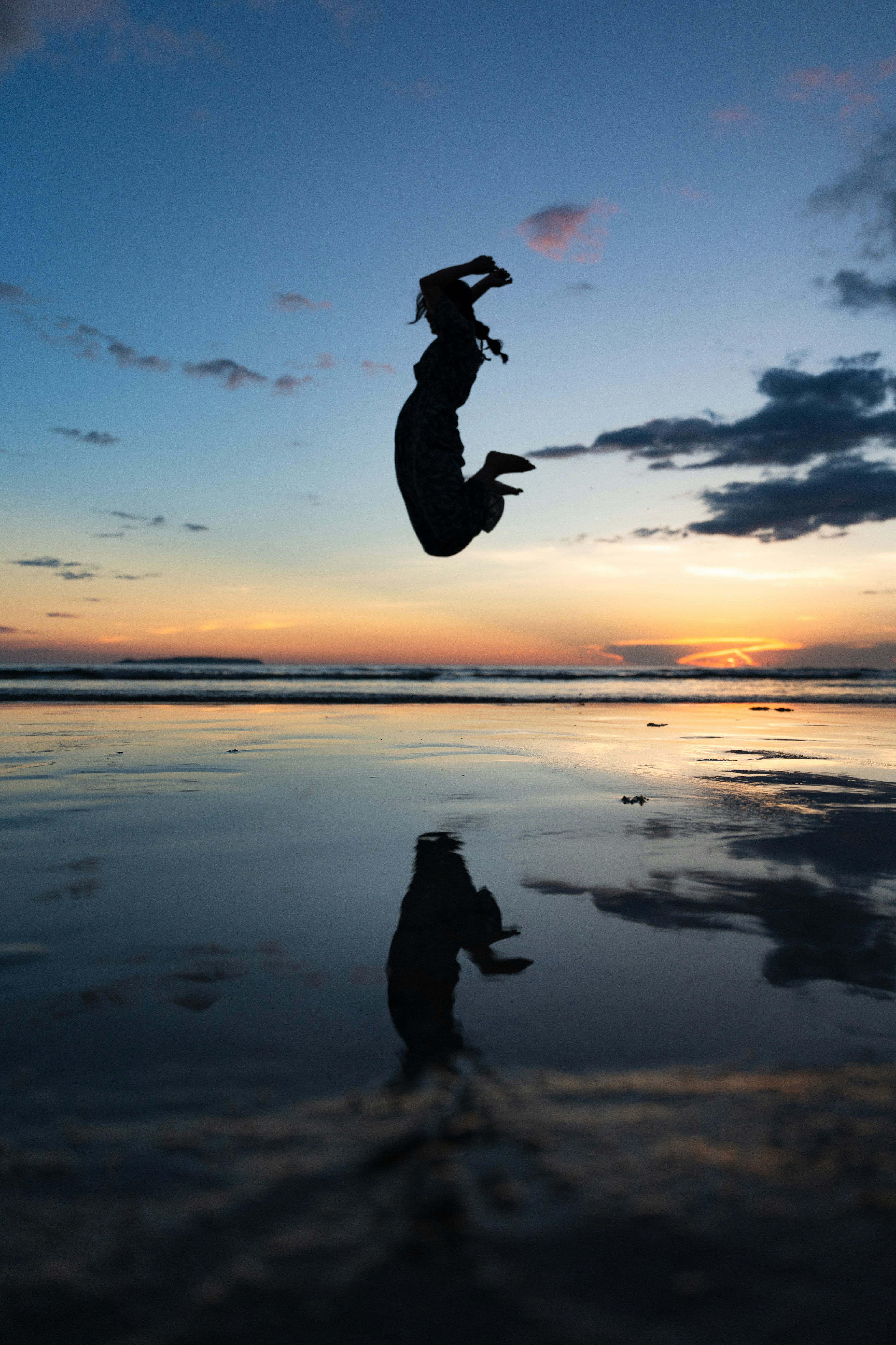 Silueta de una persona saltando en el mar al atardecer