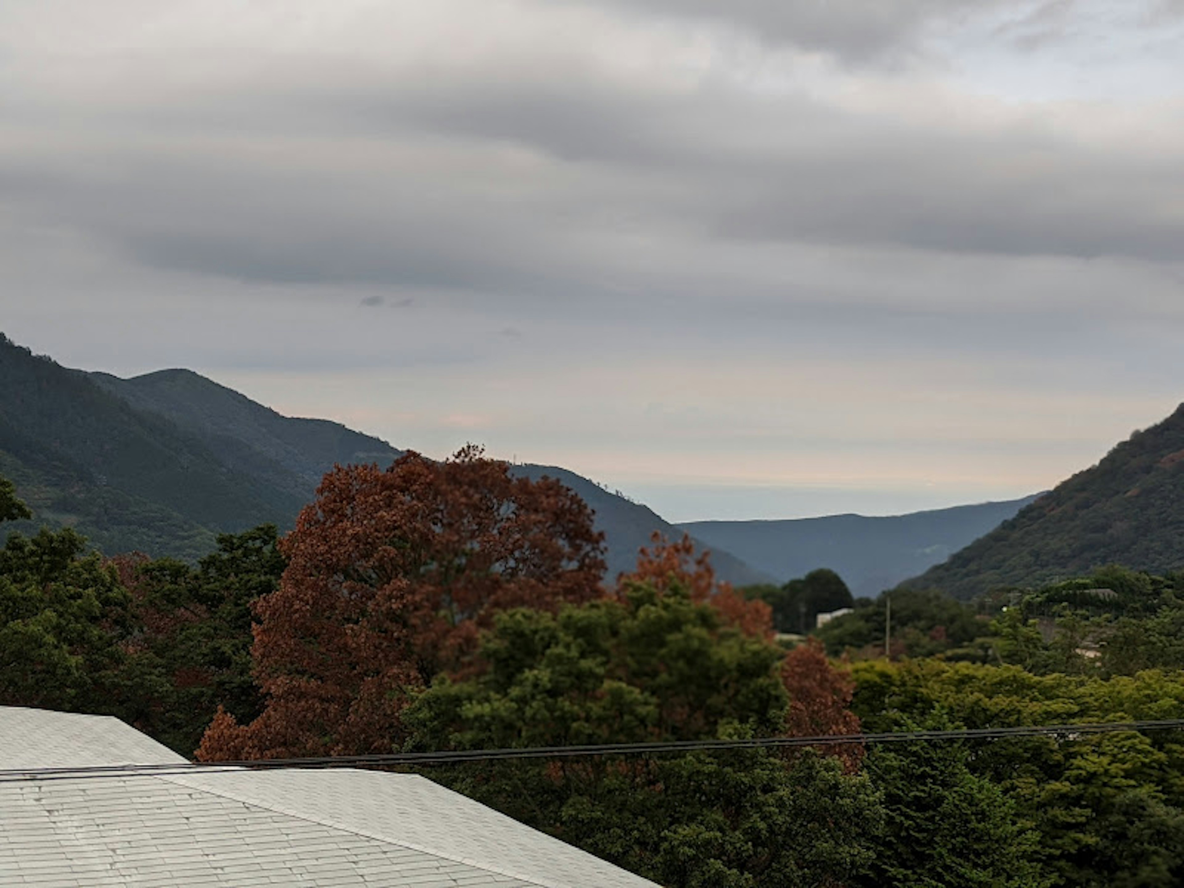 Vista escénica de montañas con árboles coloridos bajo un cielo nublado