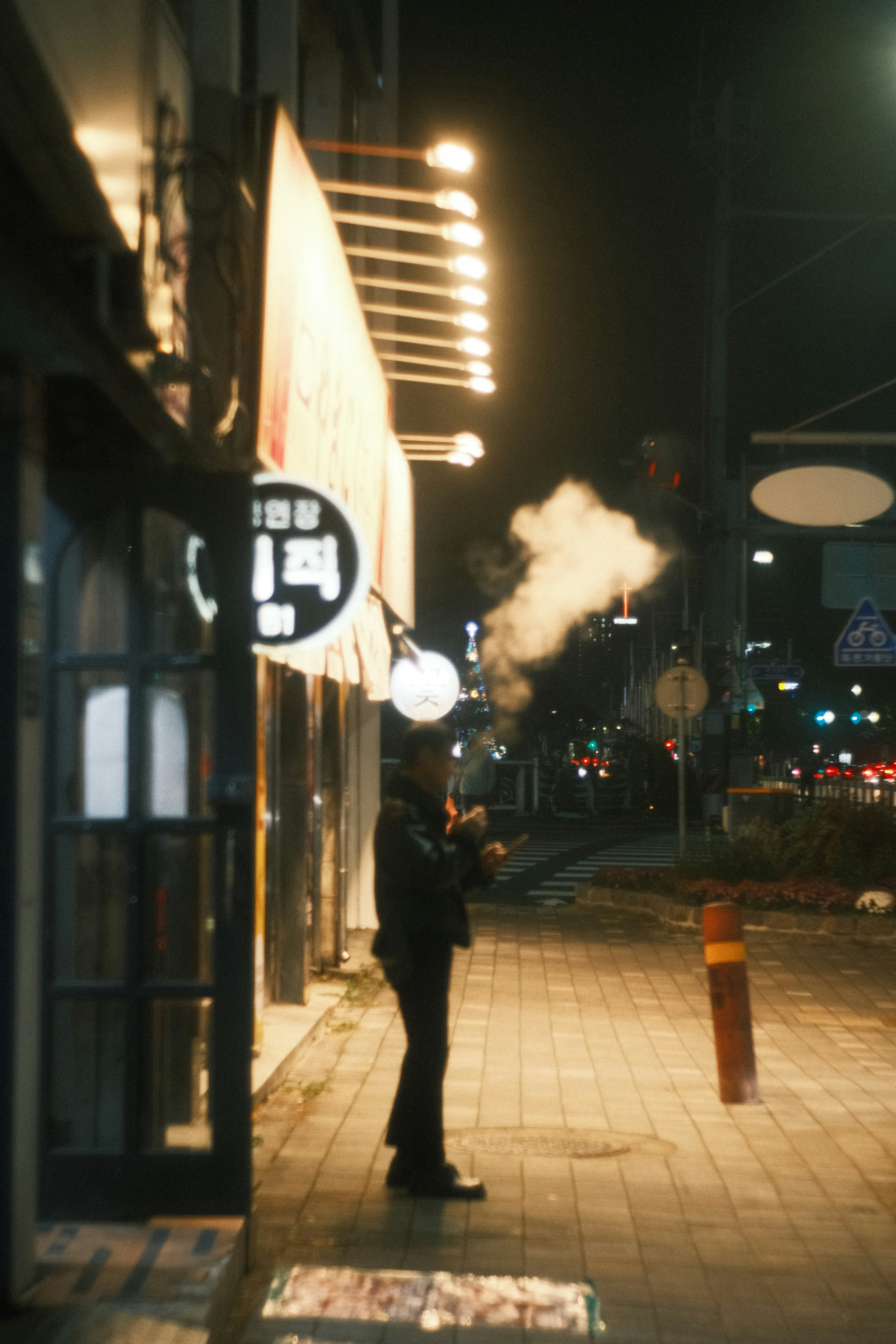 夜晚街角吸烟的人和亮灯的商店标志