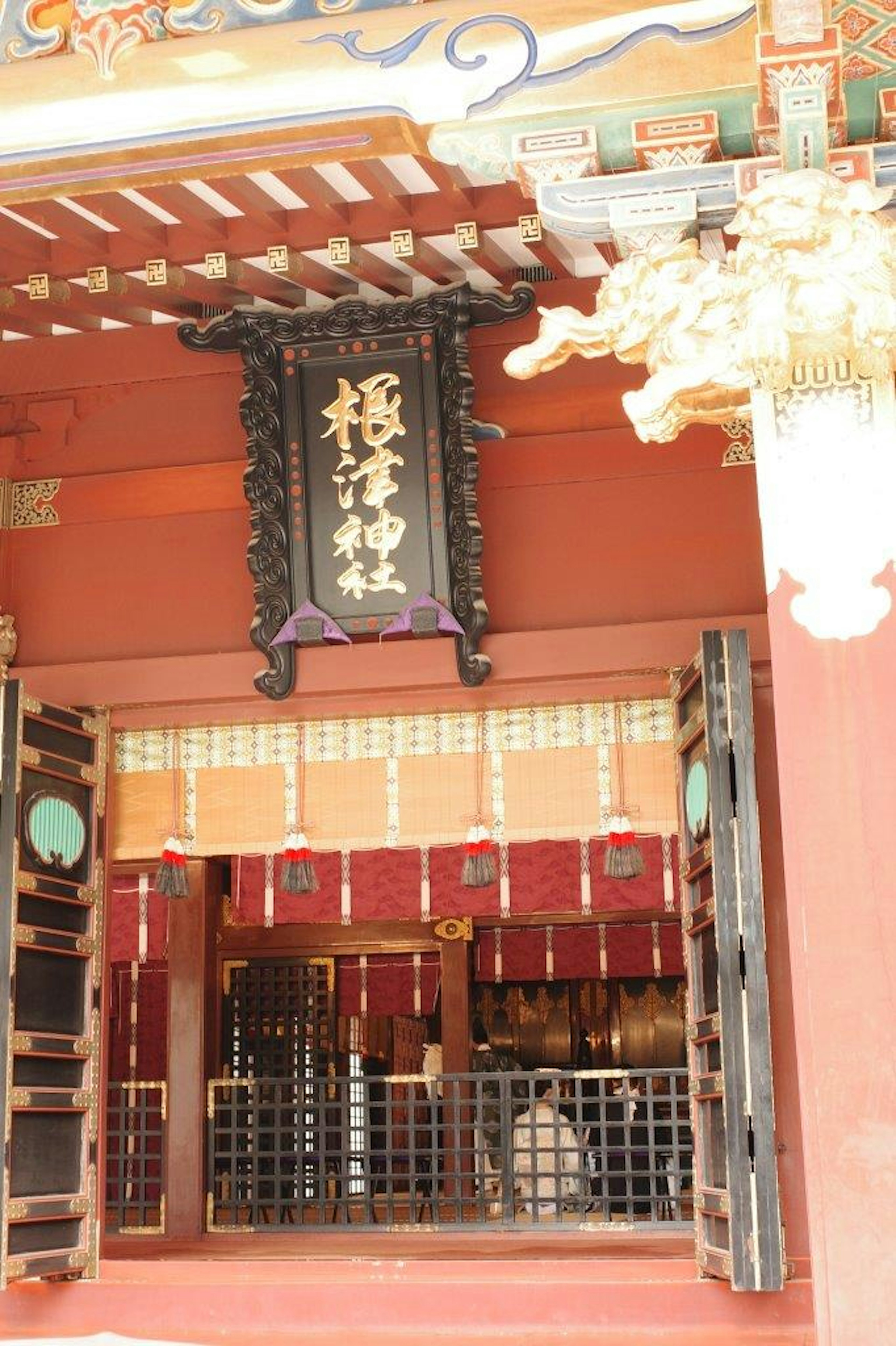 Entrée d'un sanctuaire japonais traditionnel avec des portes décoratives et un panneau