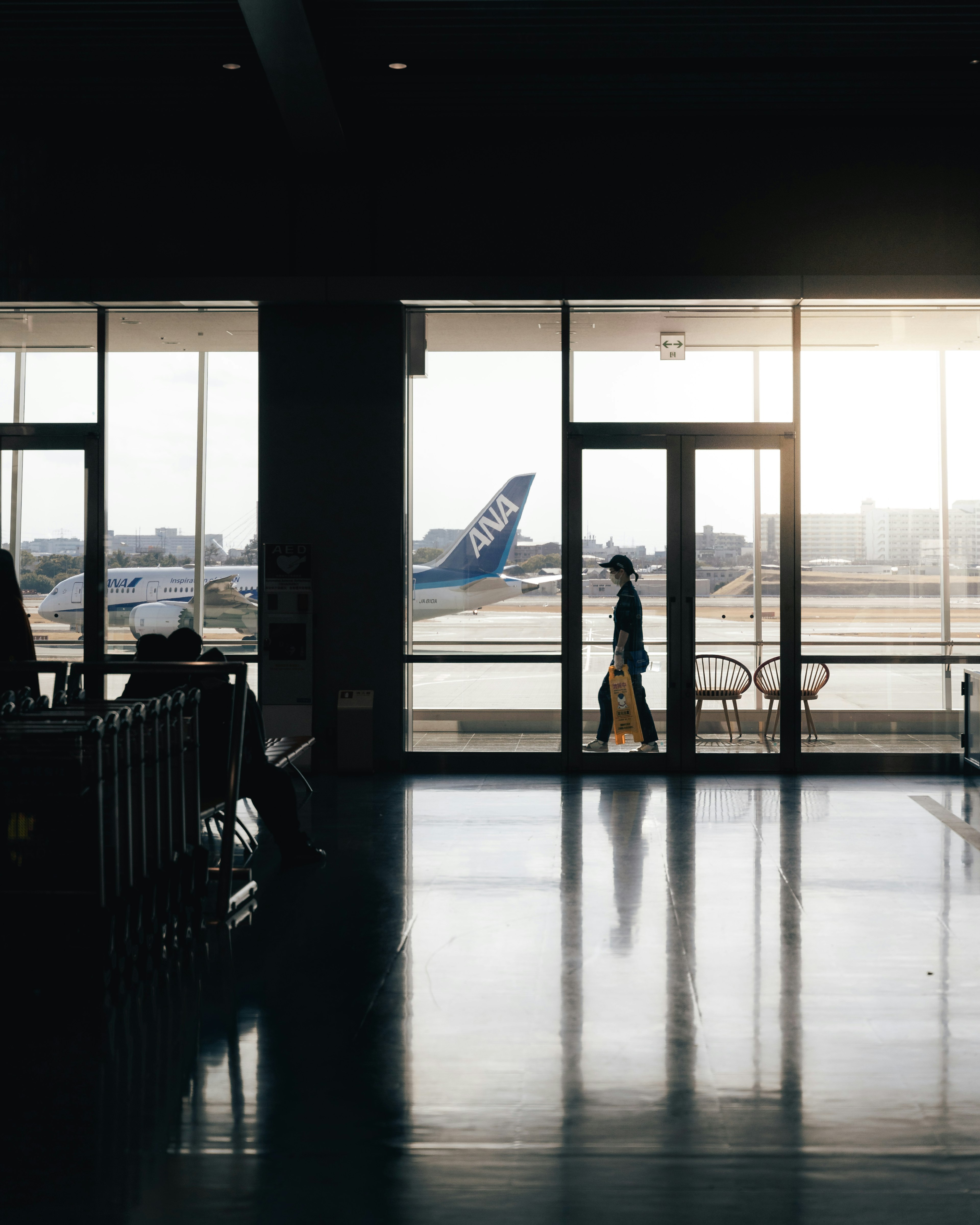 공항 터미널 안을 걷고 있는 사람의 실루엣과 외부의 비행기