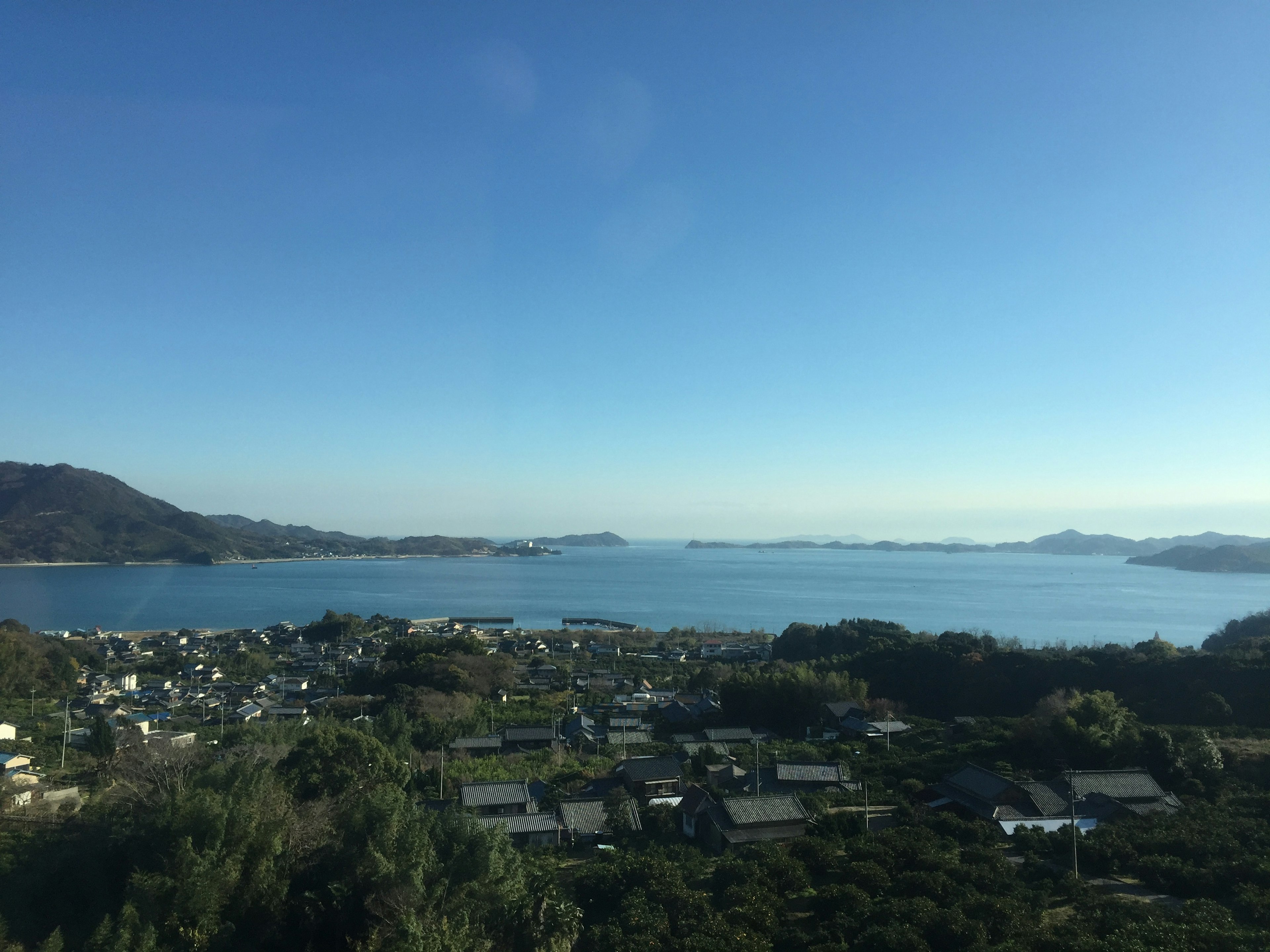 Malersicher Blick auf das blaue Meer und den Himmel mit Dorf und Bergen