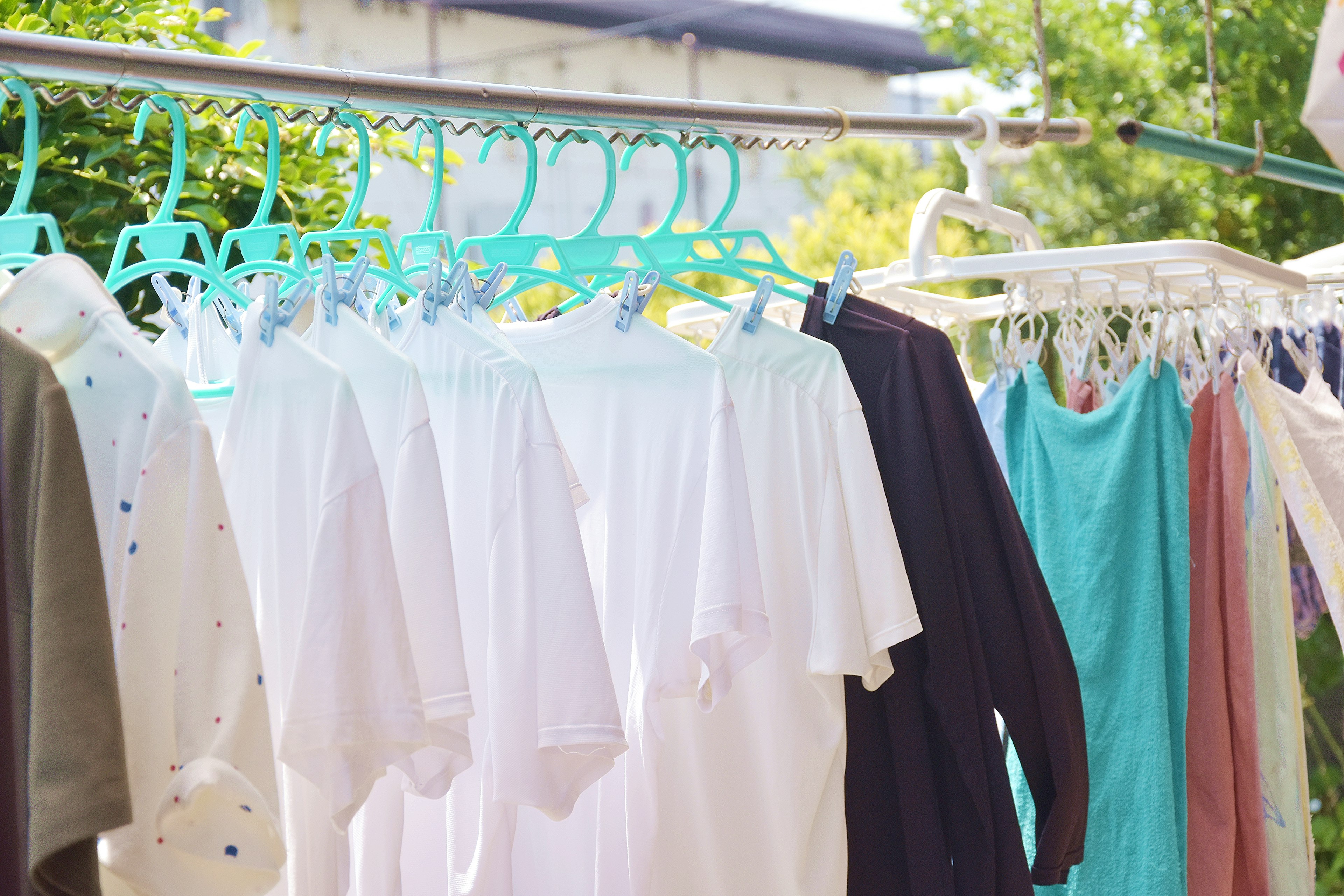 Ropa secándose en perchas turquesas con camisetas blancas y prendas coloridas