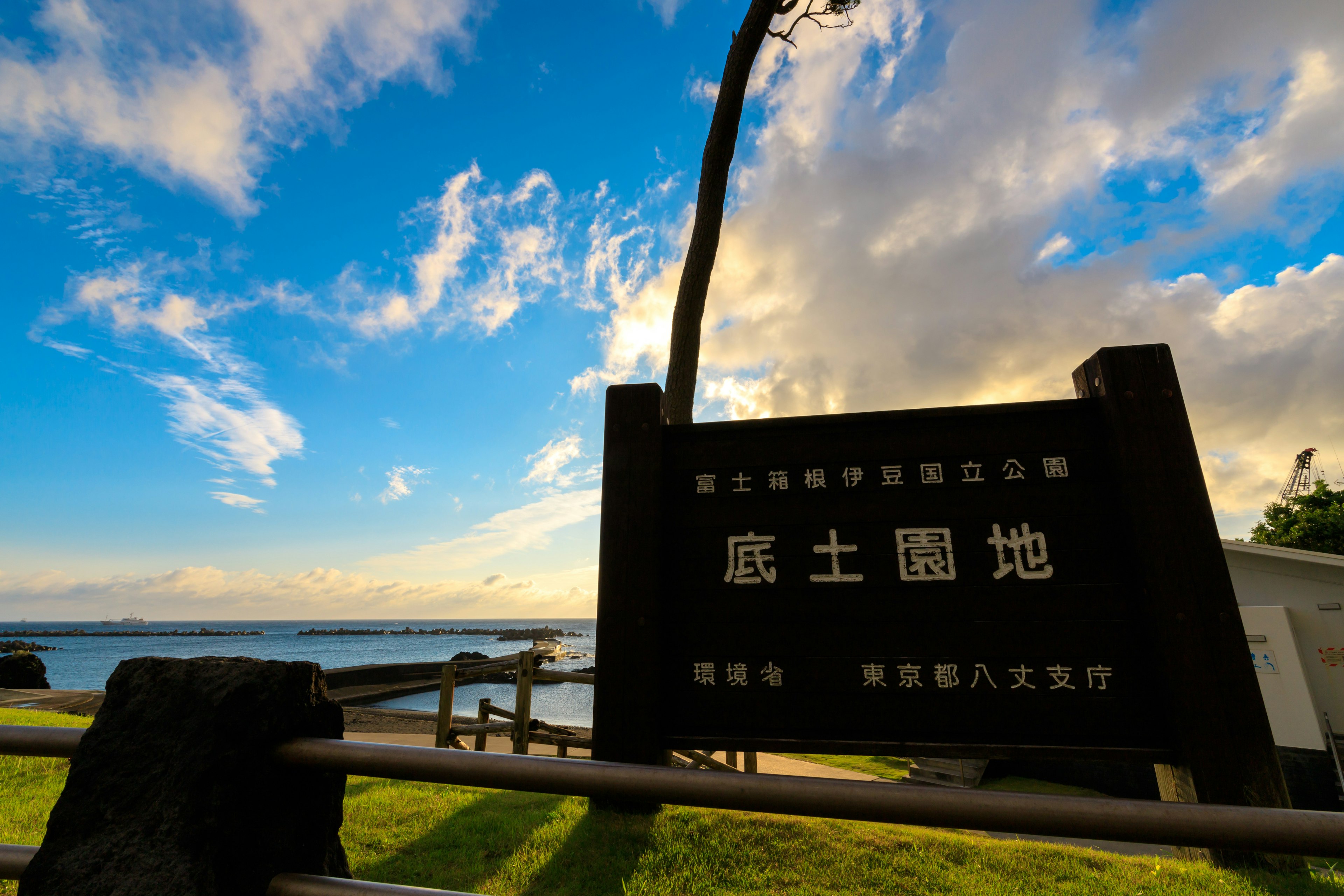 Coastal view with blue sky and white clouds featuring a Japanese sign