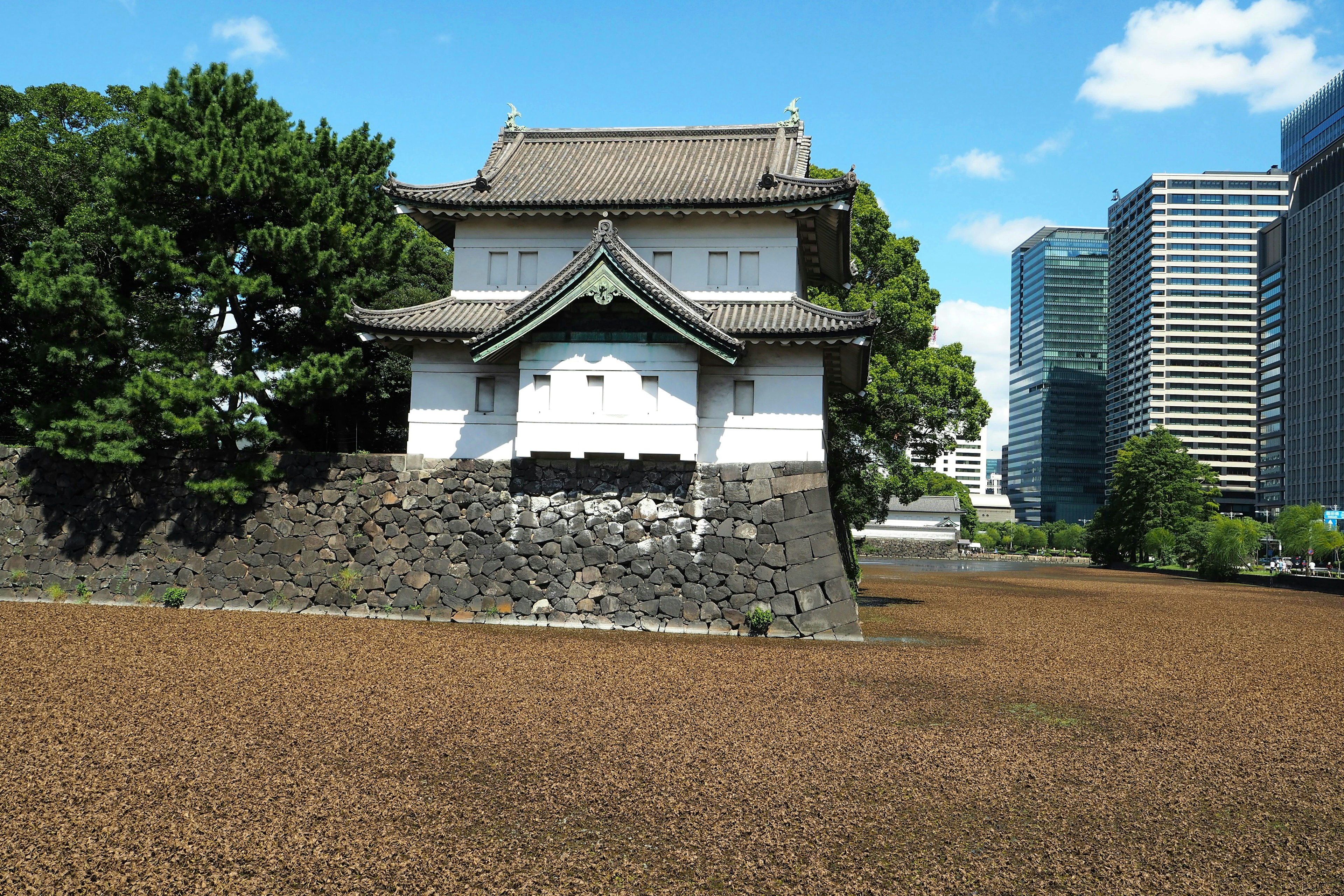 Weiße Burgpforte am äußeren Graben des Kaiserpalastes in Tokio mit grünen Bäumen