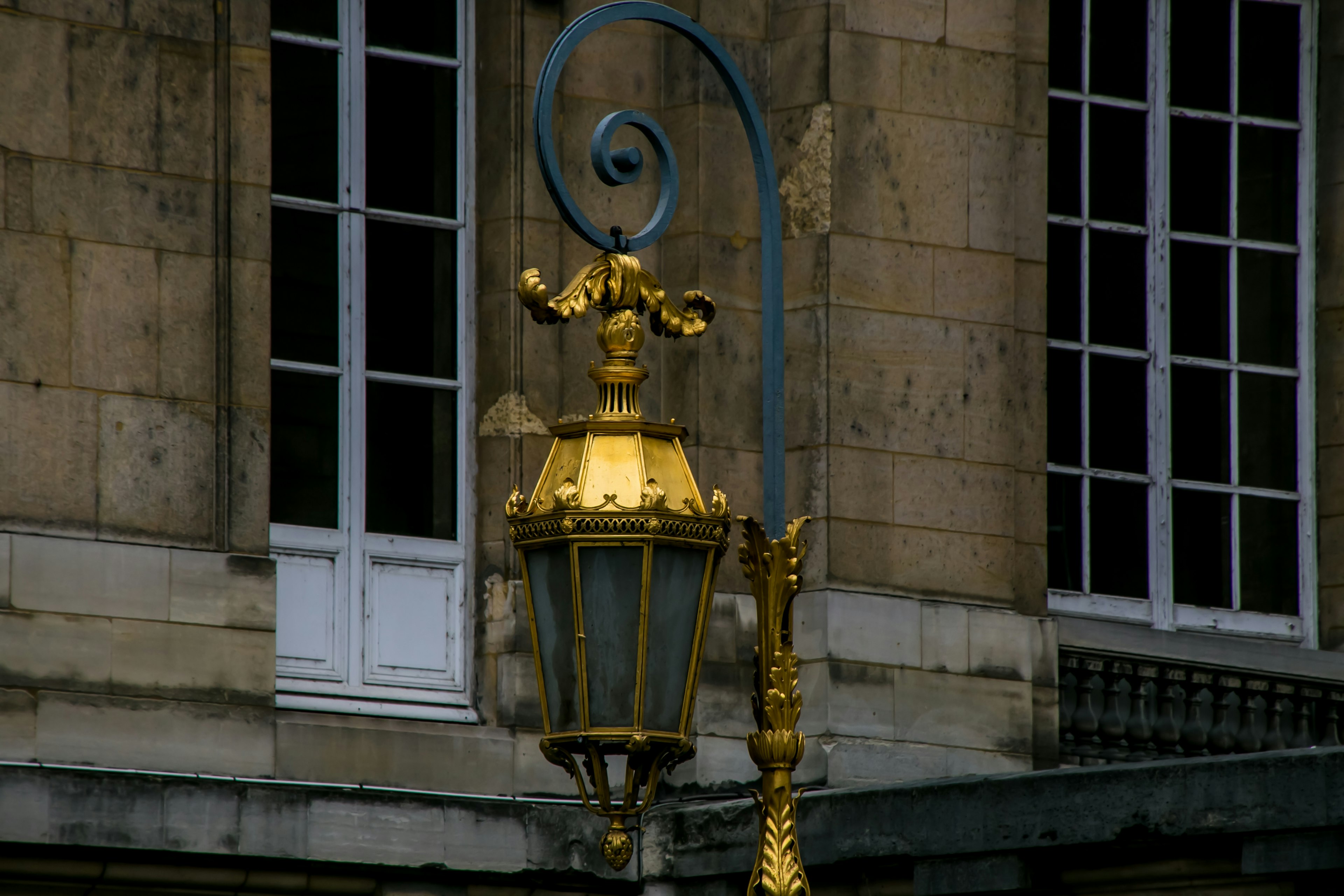 Farola dorada con un remolino decorativo cerca de ventanas blancas