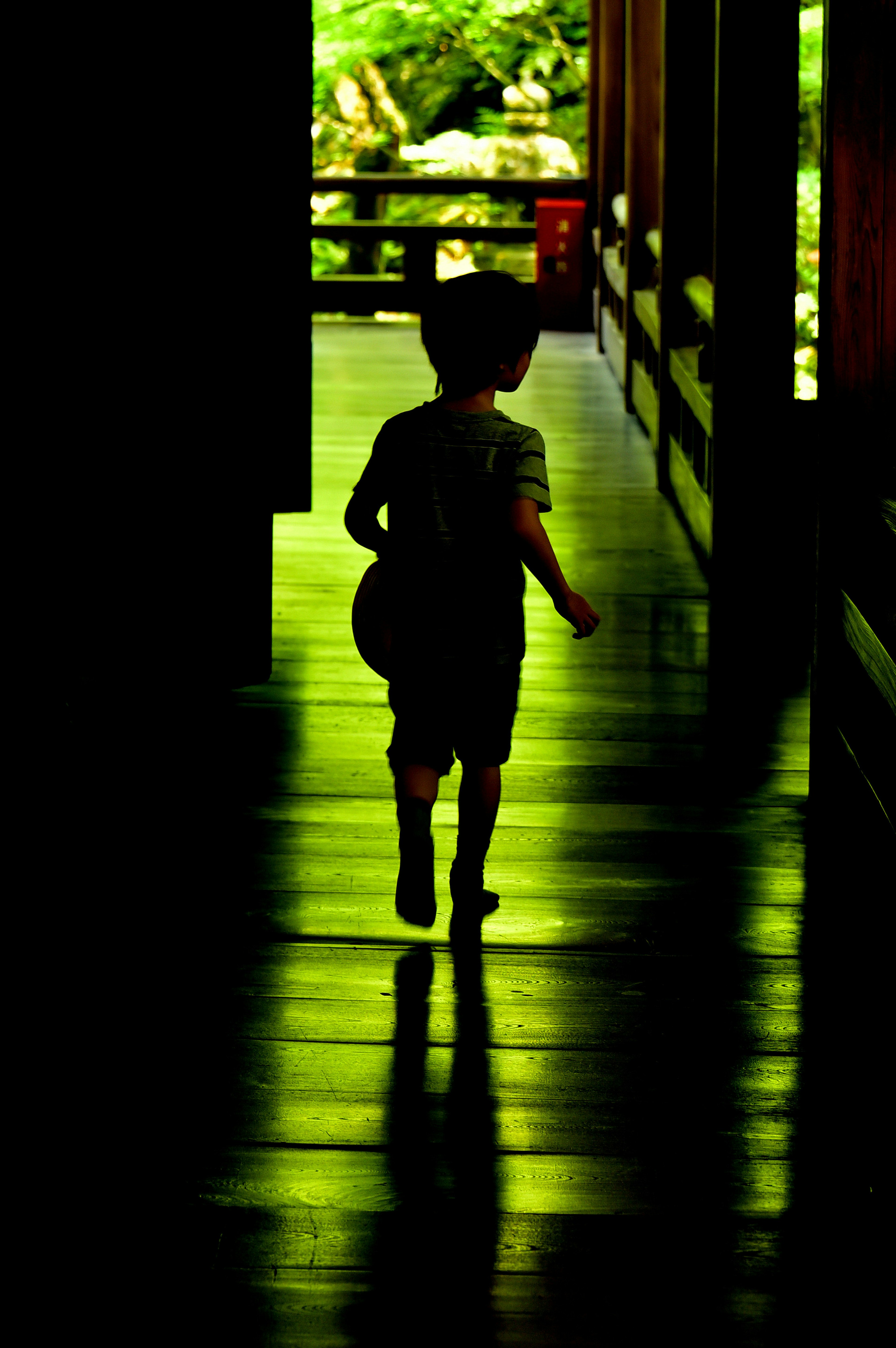 Seorang anak berlari di lorong dengan siluet di latar belakang hijau