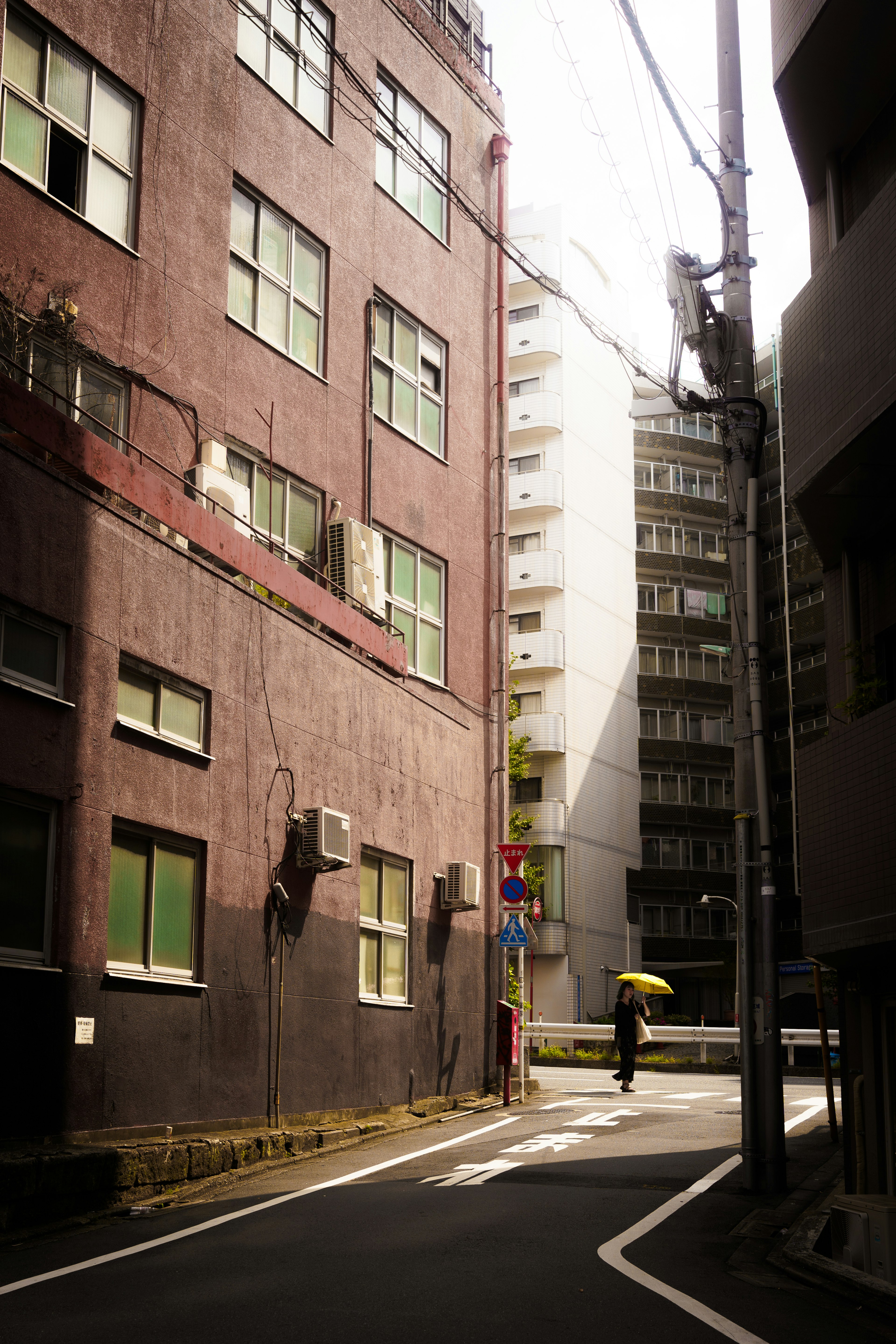 Calle estrecha con edificios y una persona con un paraguas