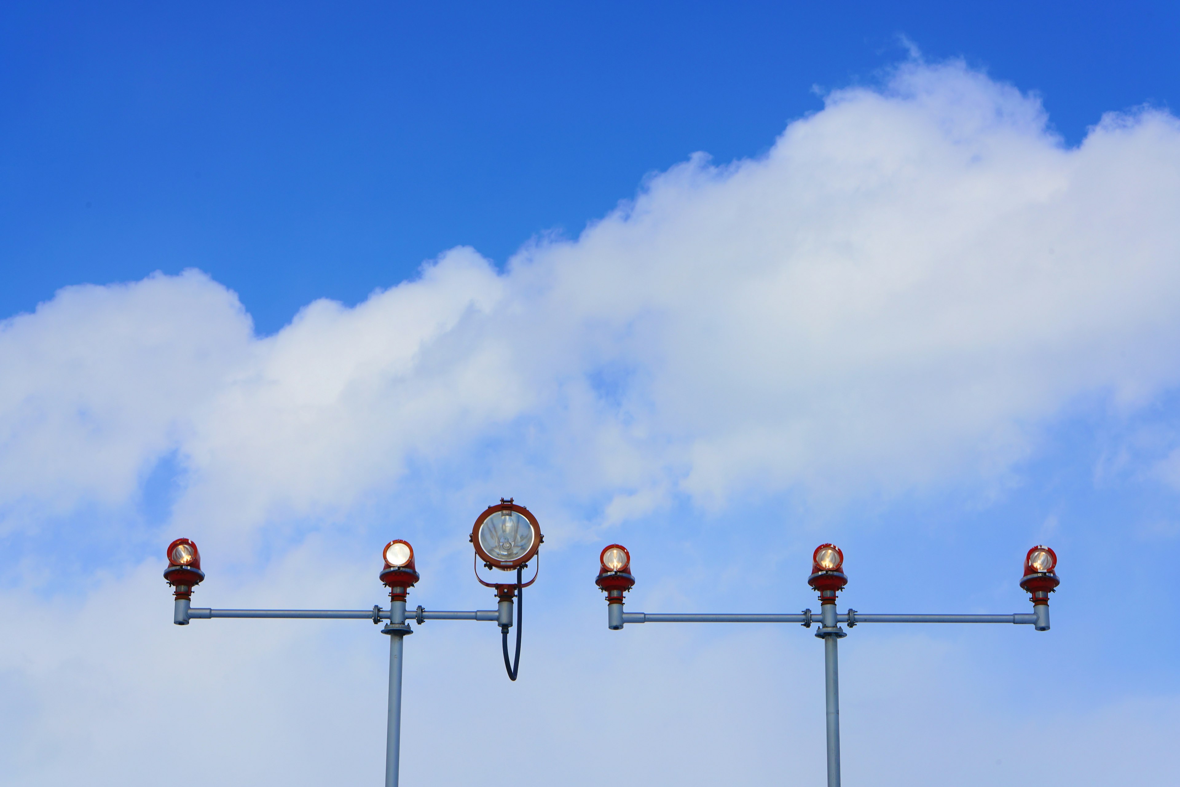 Multiple aviation lights installed under a blue sky with clouds