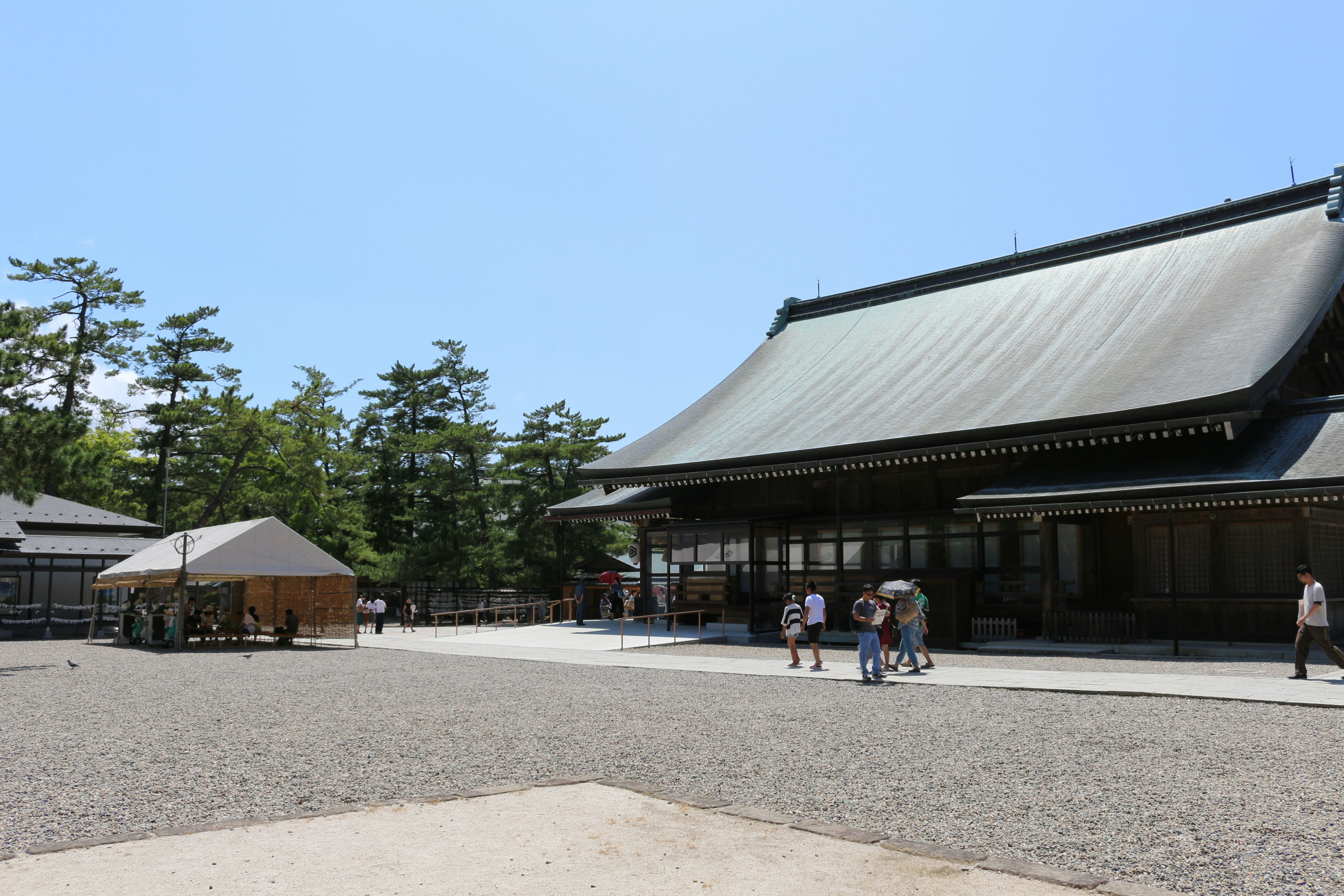 Traditionelles japanisches Tempelgebäude, umgeben von einem weitläufigen Garten mit Menschen