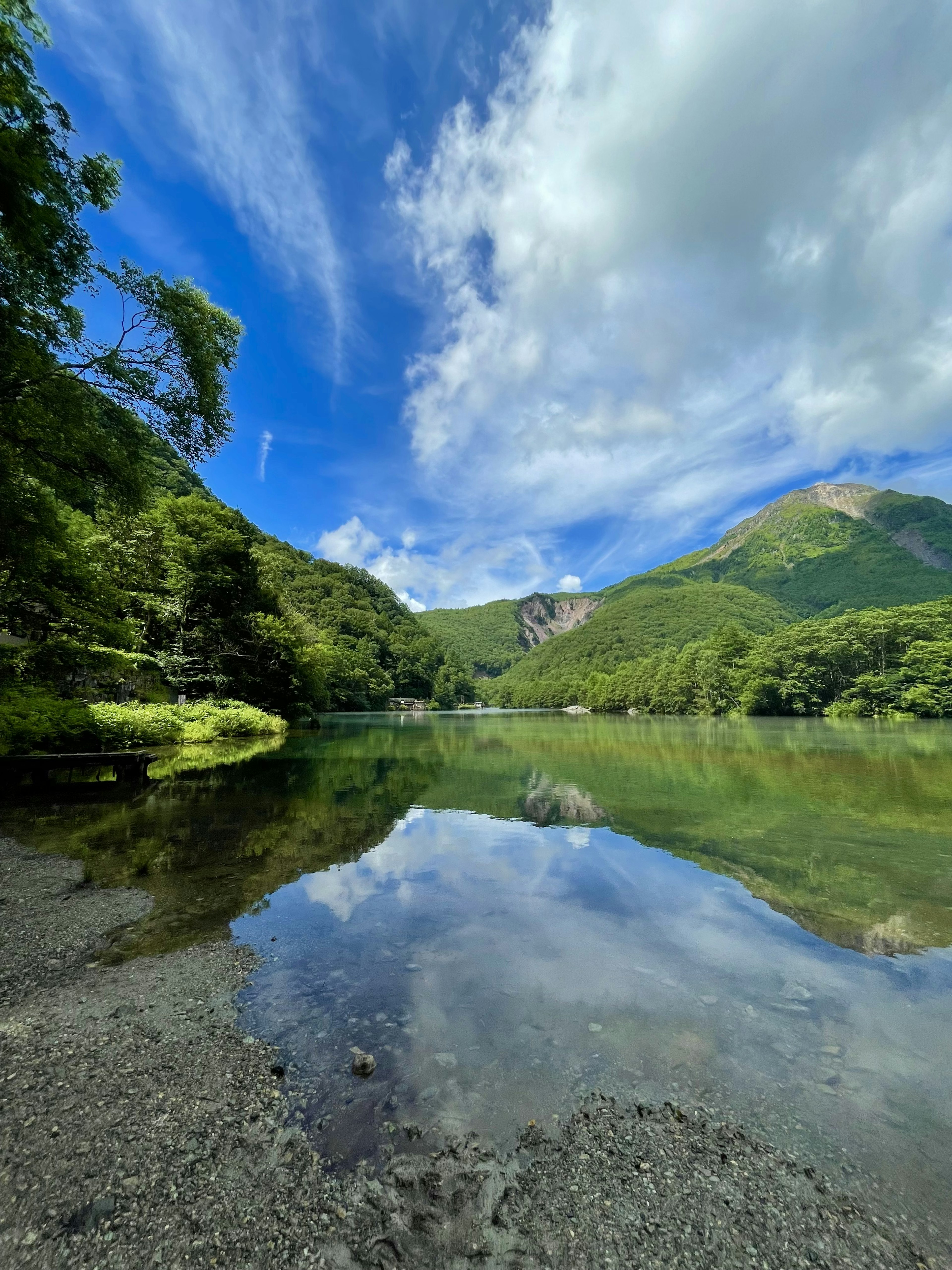 緑豊かな山々と青空を映し出す静かな湖の風景