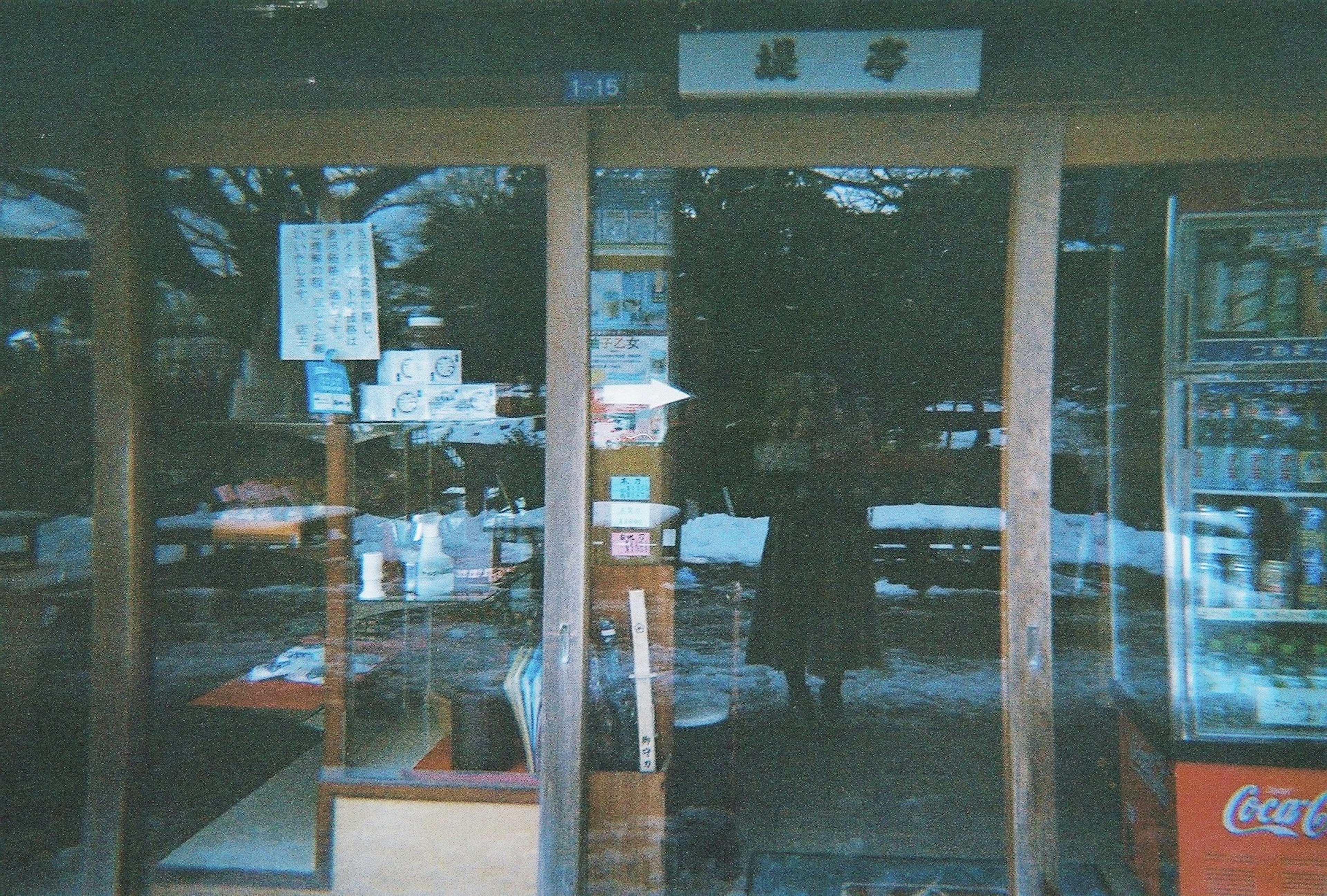 Exterior view of a wooden storefront with a sign and reflections