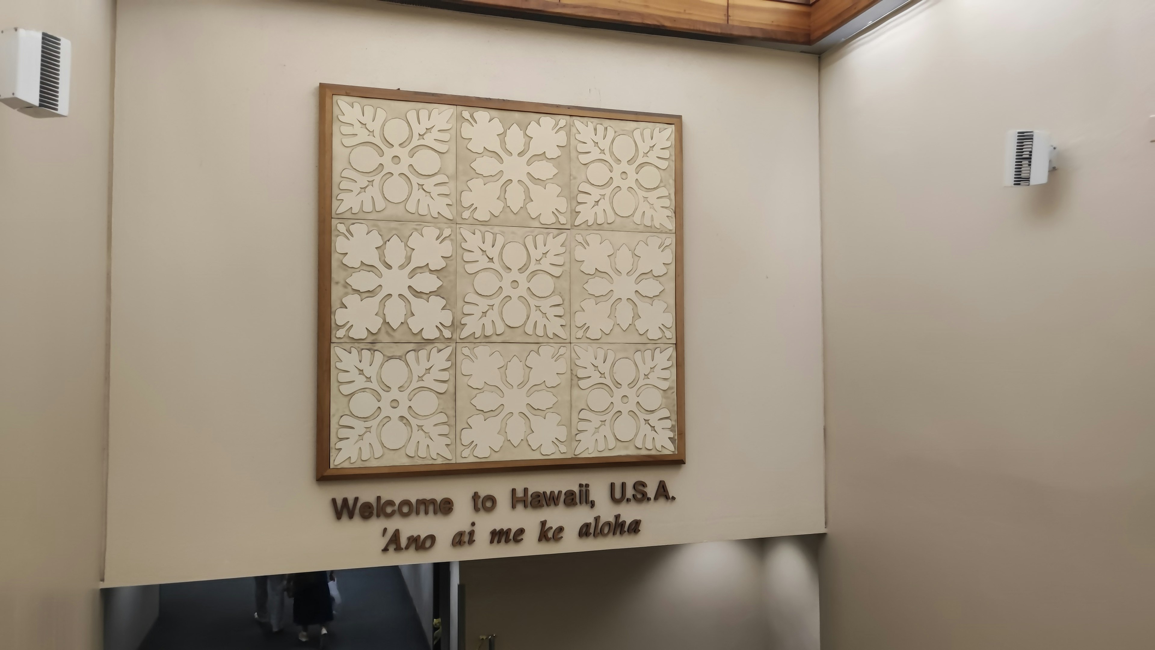 A tapestry artwork on the wall featuring a welcome message to Hawaii USA