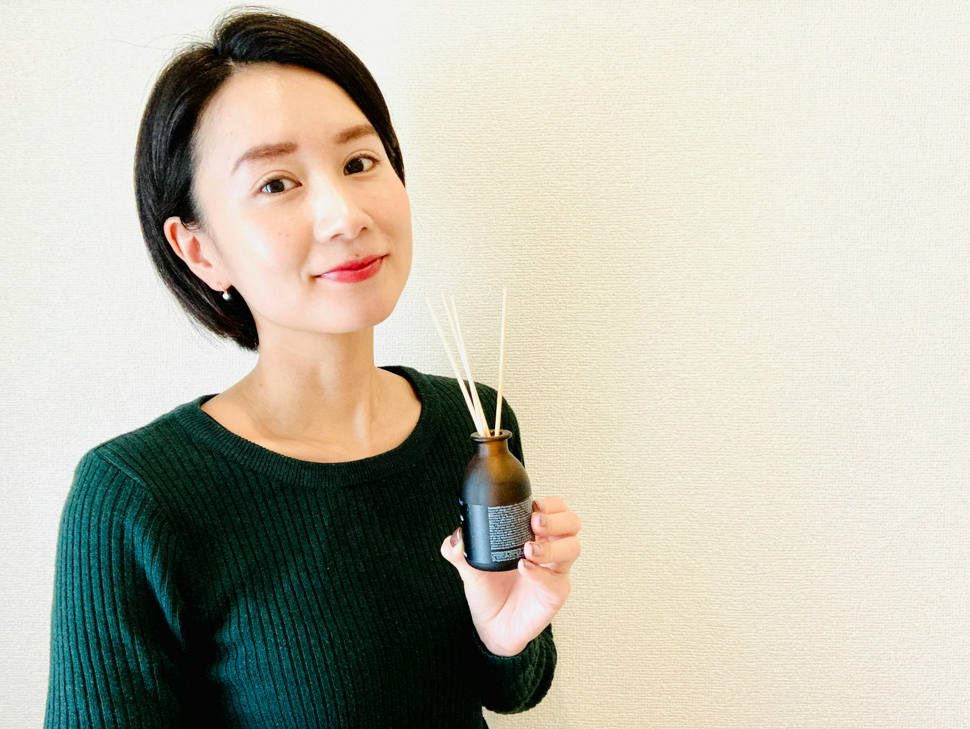 Portrait of a woman holding a black reed diffuser