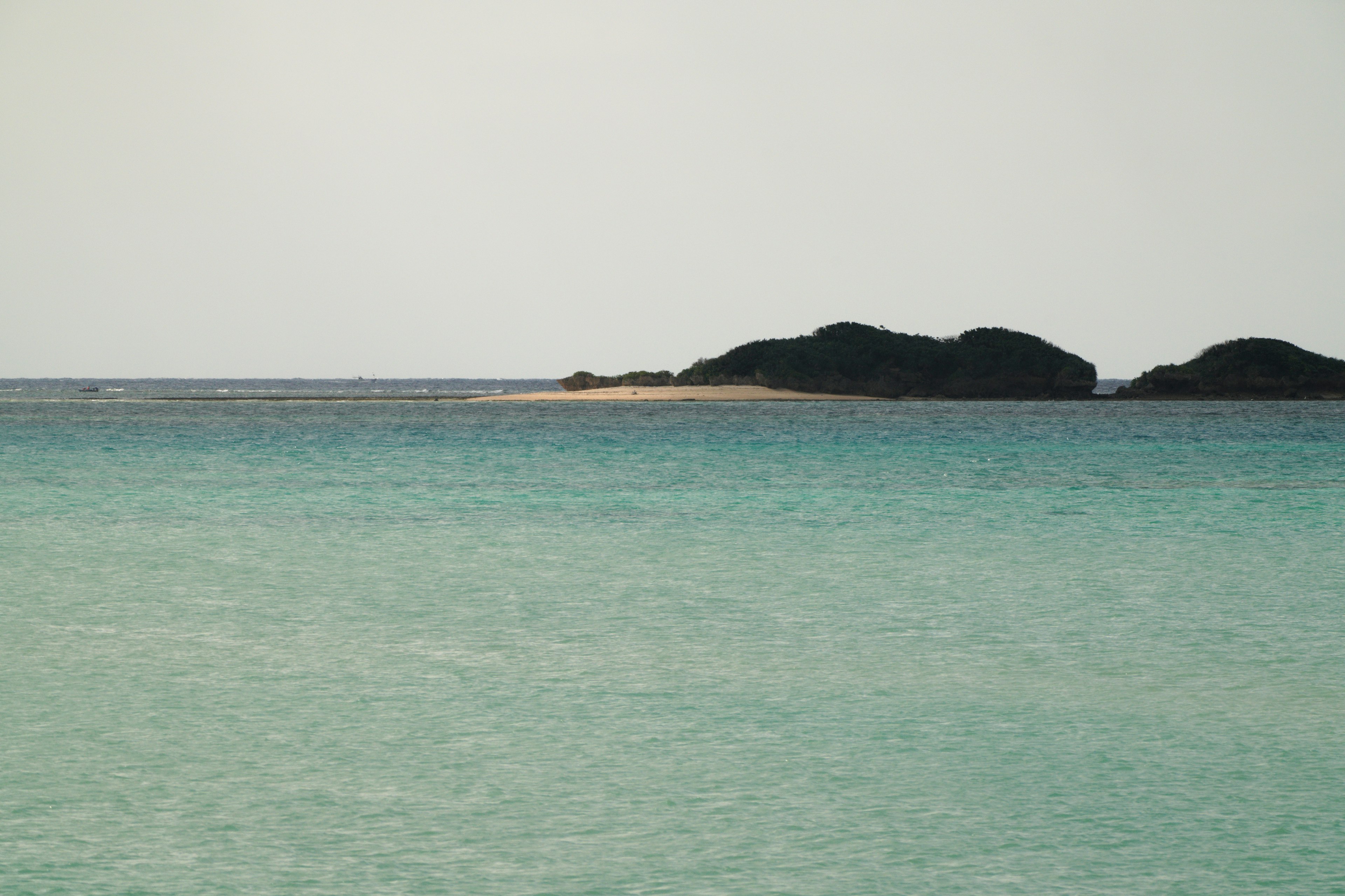 Laut biru tenang dengan pulau kecil di kejauhan