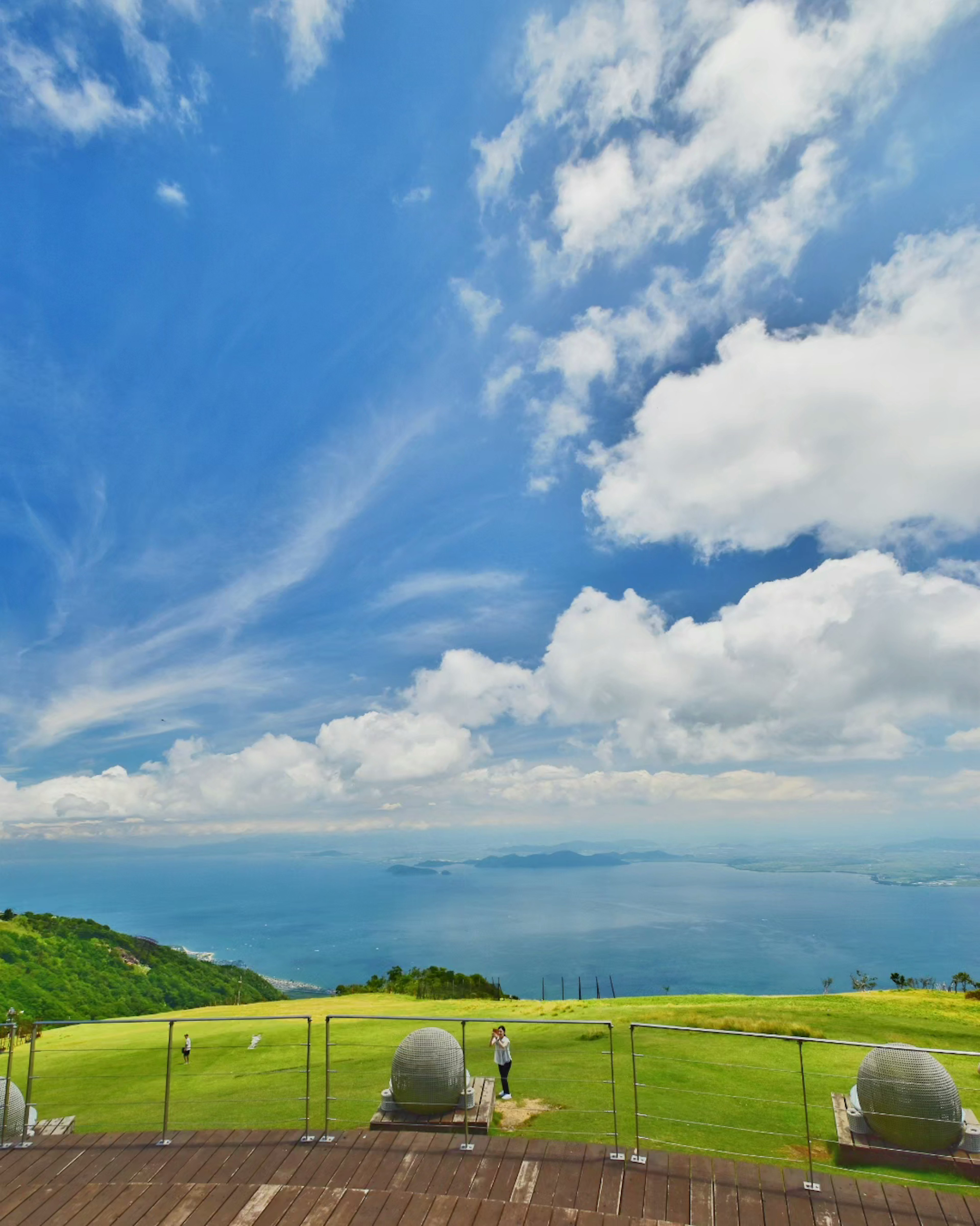 Scenic view of blue sky and white clouds overlooking a beautiful sea and green hills