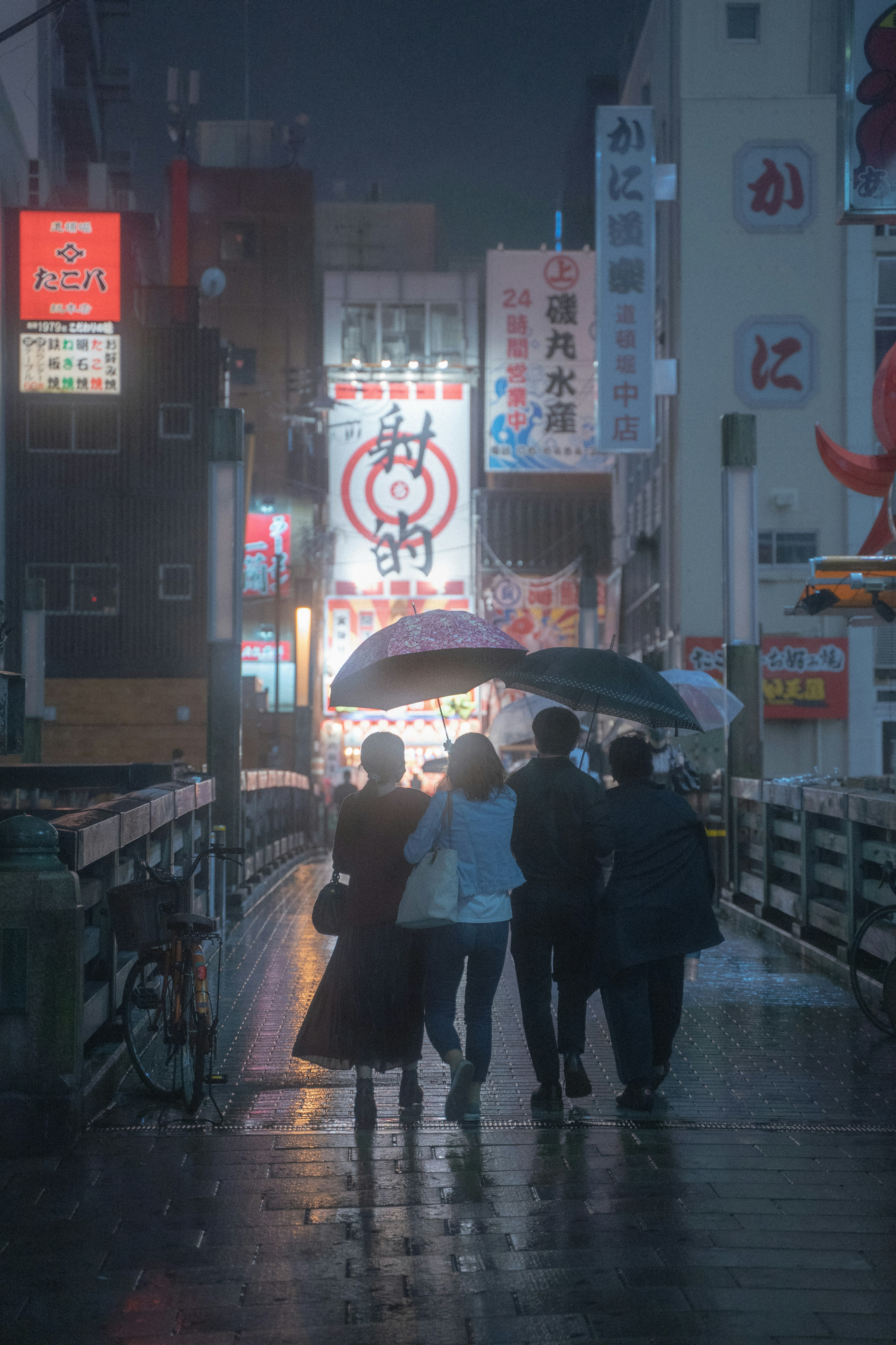 Schatten von Personen, die bei Regen unter Regenschirmen gehen, mit lebhaften Neonlichtern in einer belebten Stadt