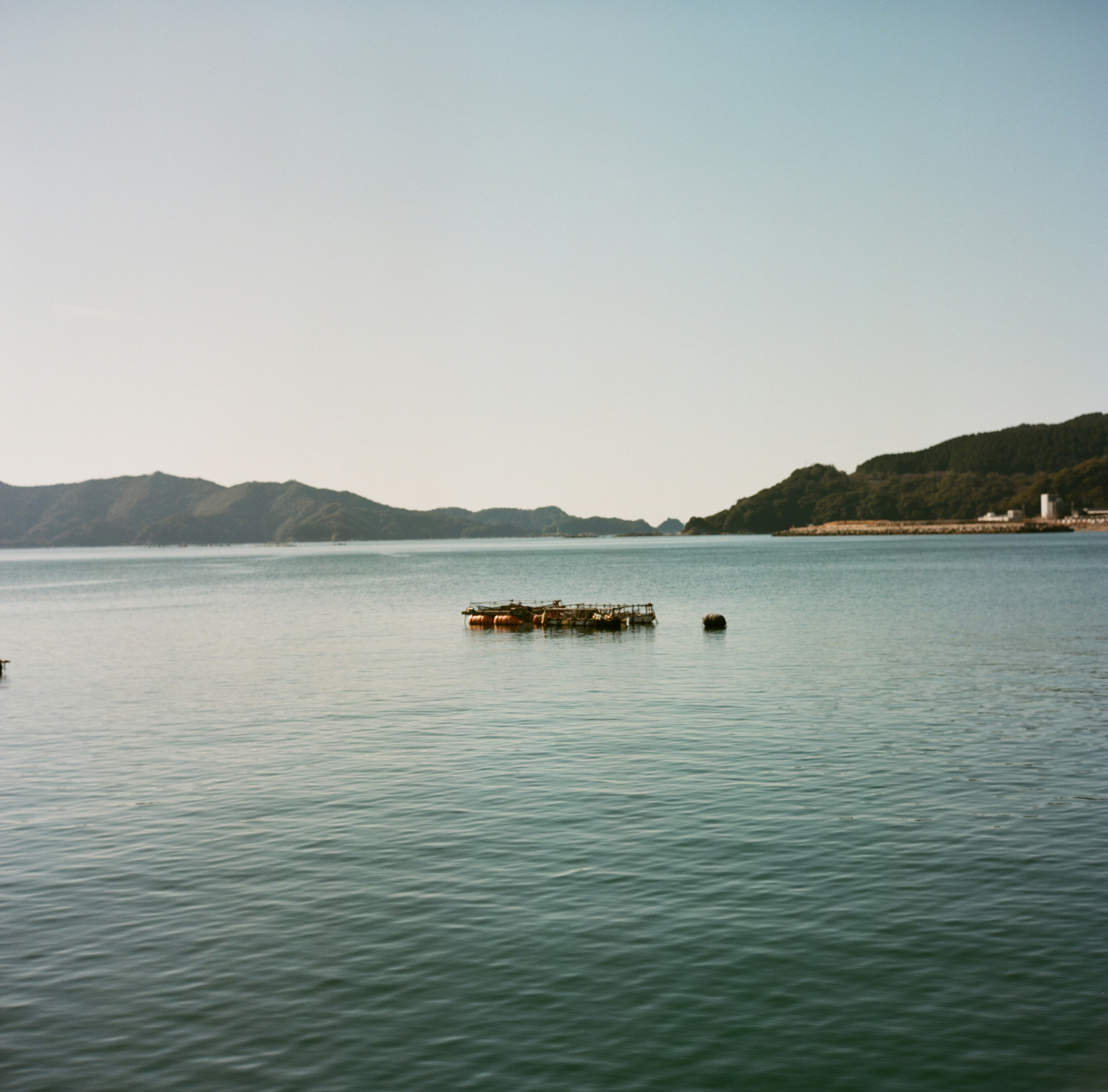 Calm sea with distant mountains and a floating dock