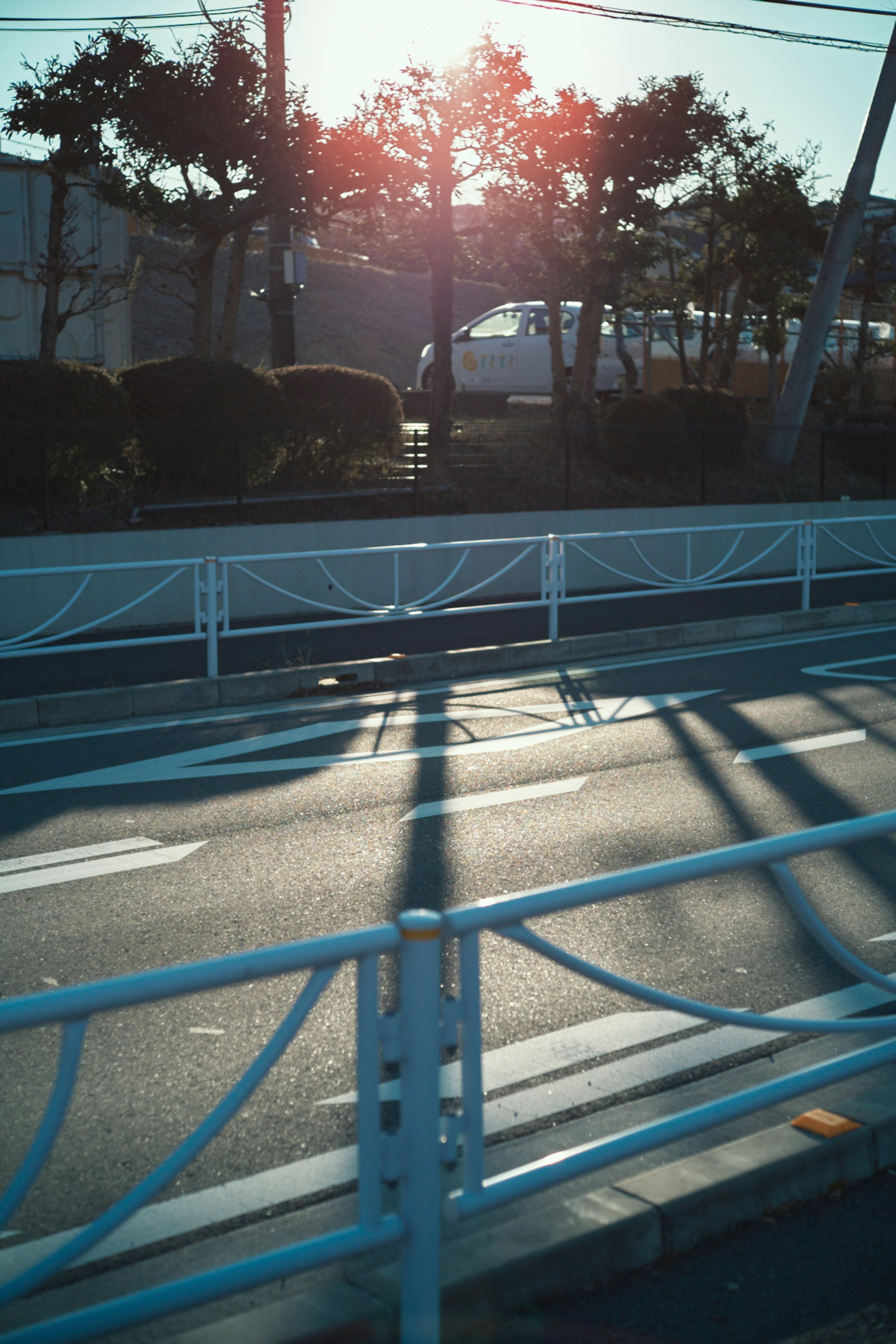 夕日の光が反射する道路と白いフェンスの風景