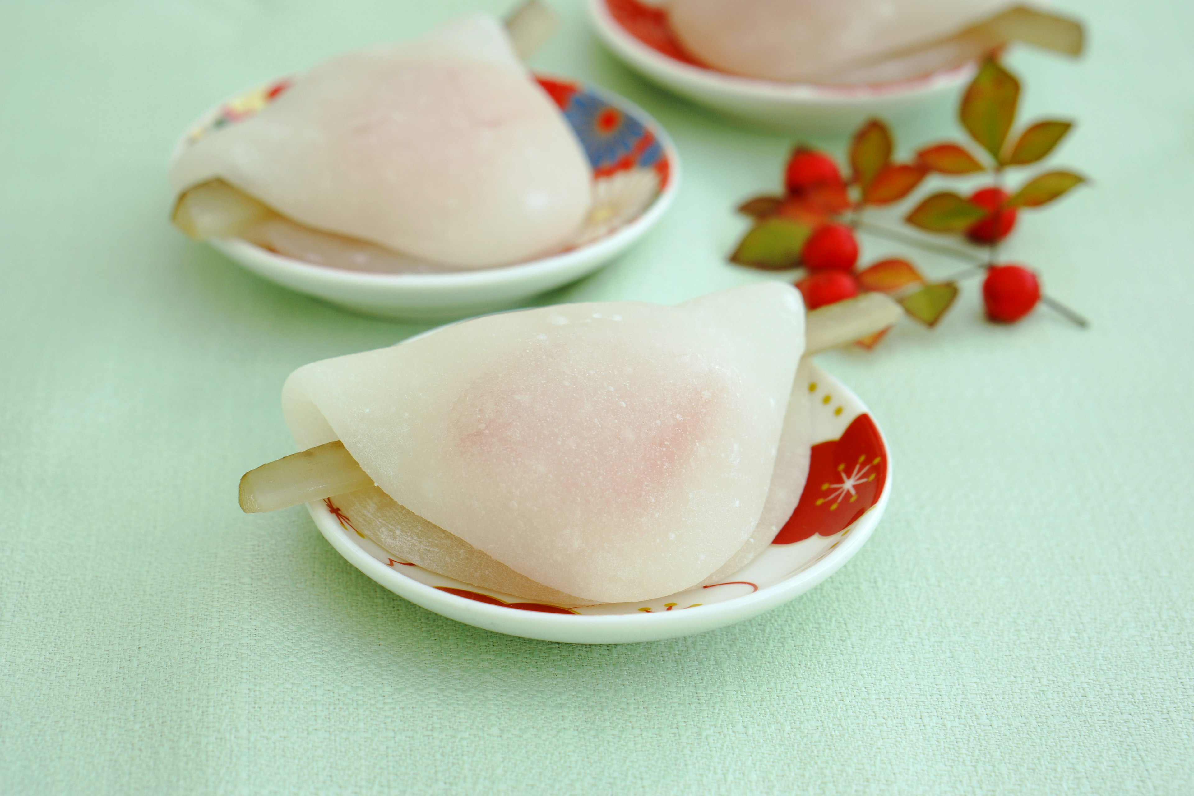 Hermosa presentación de dulces japoneses con mochi rosa claro y hojas decorativas