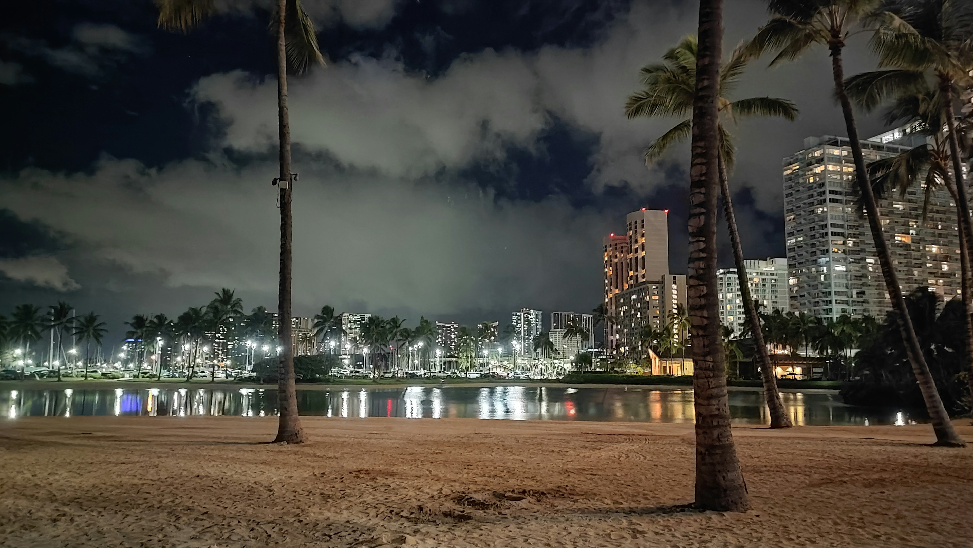 威基基海灘的夜景，燈火通明的建築物和反射的水面