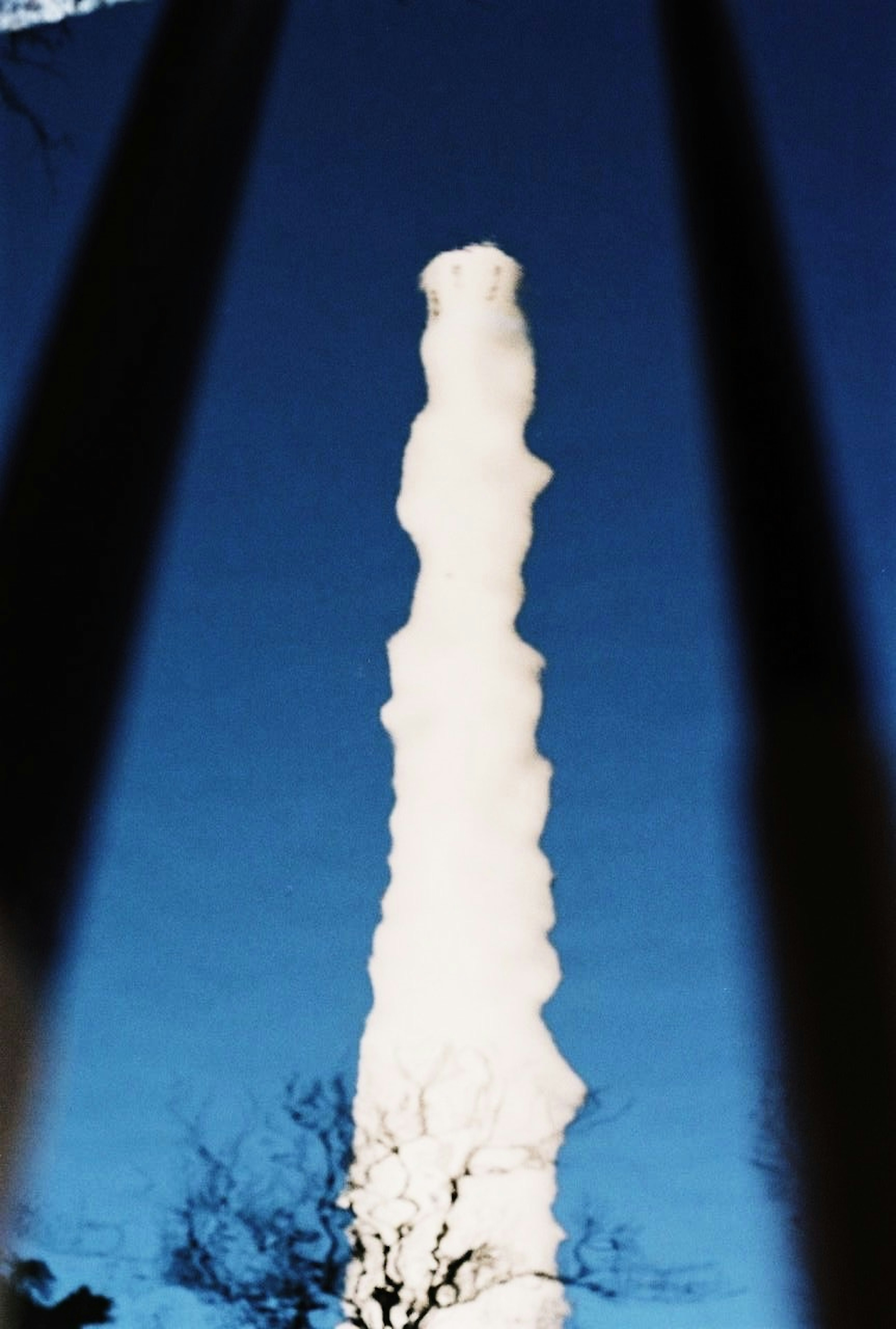 A tall column of white smoke against a blue sky