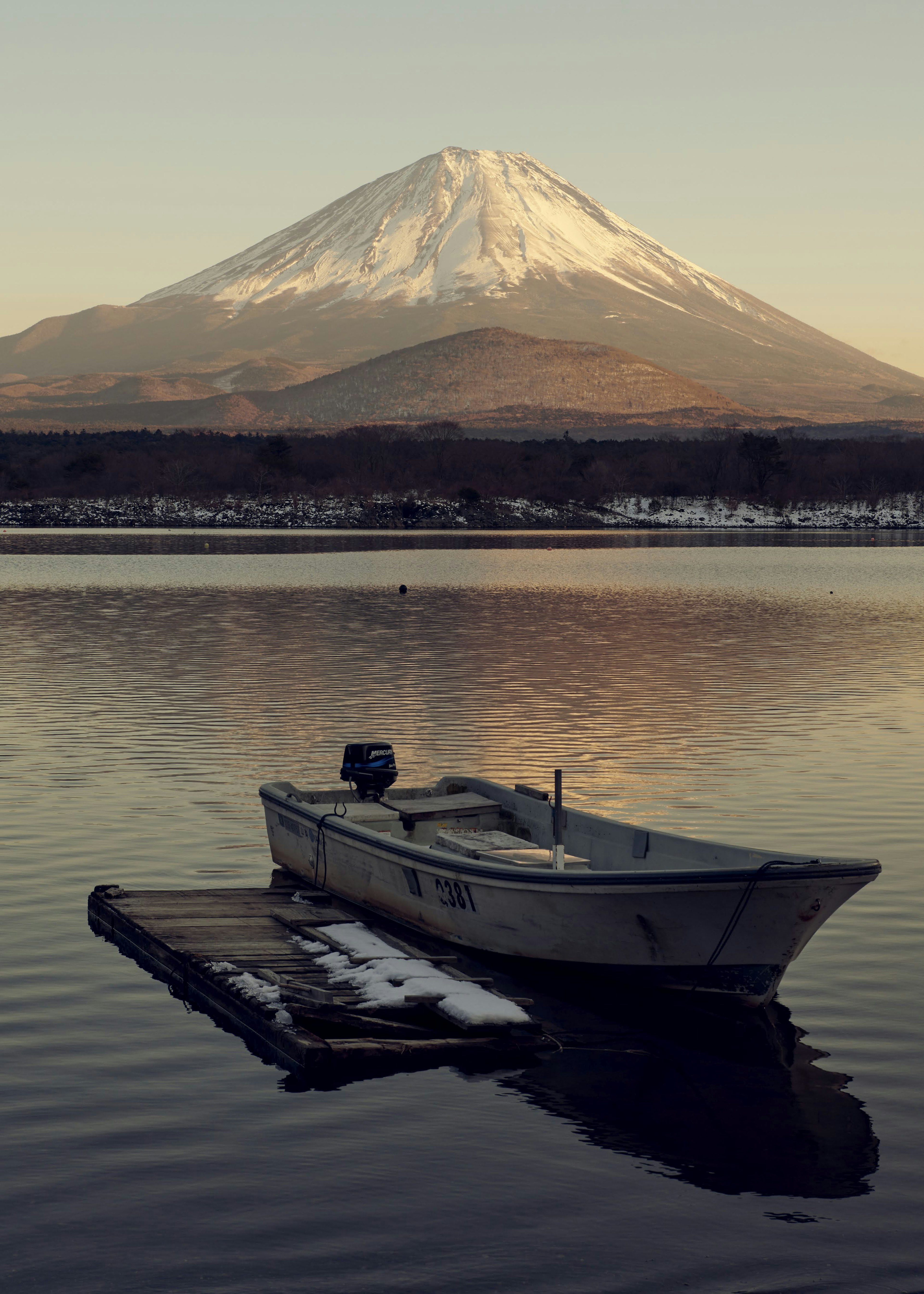 一只小船漂浮在宁静的湖面上，背景是富士山