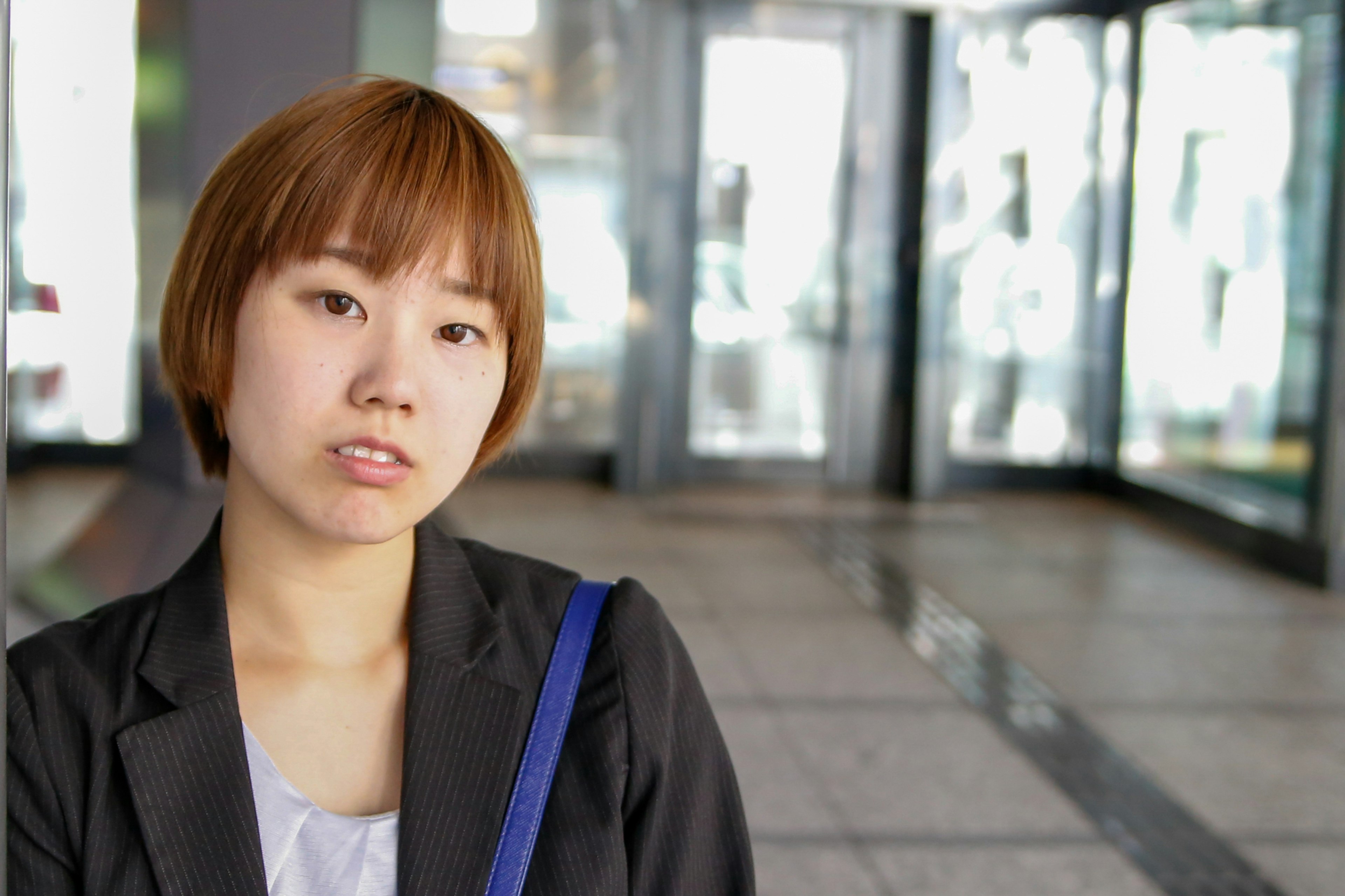 A woman in a business suit poses in front of glass doors