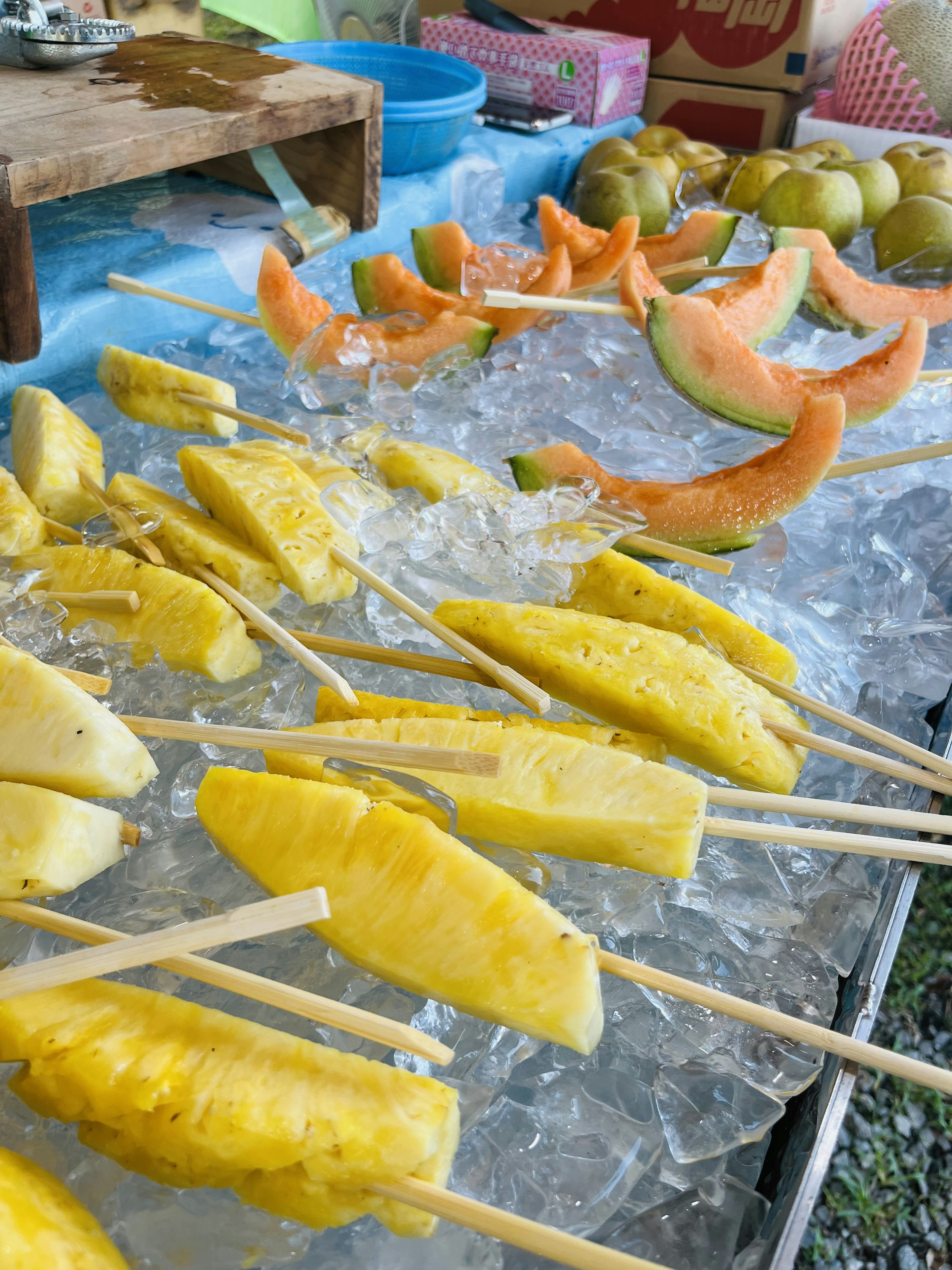 Brochetas de frutas dispuestas sobre hielo con piña y melón