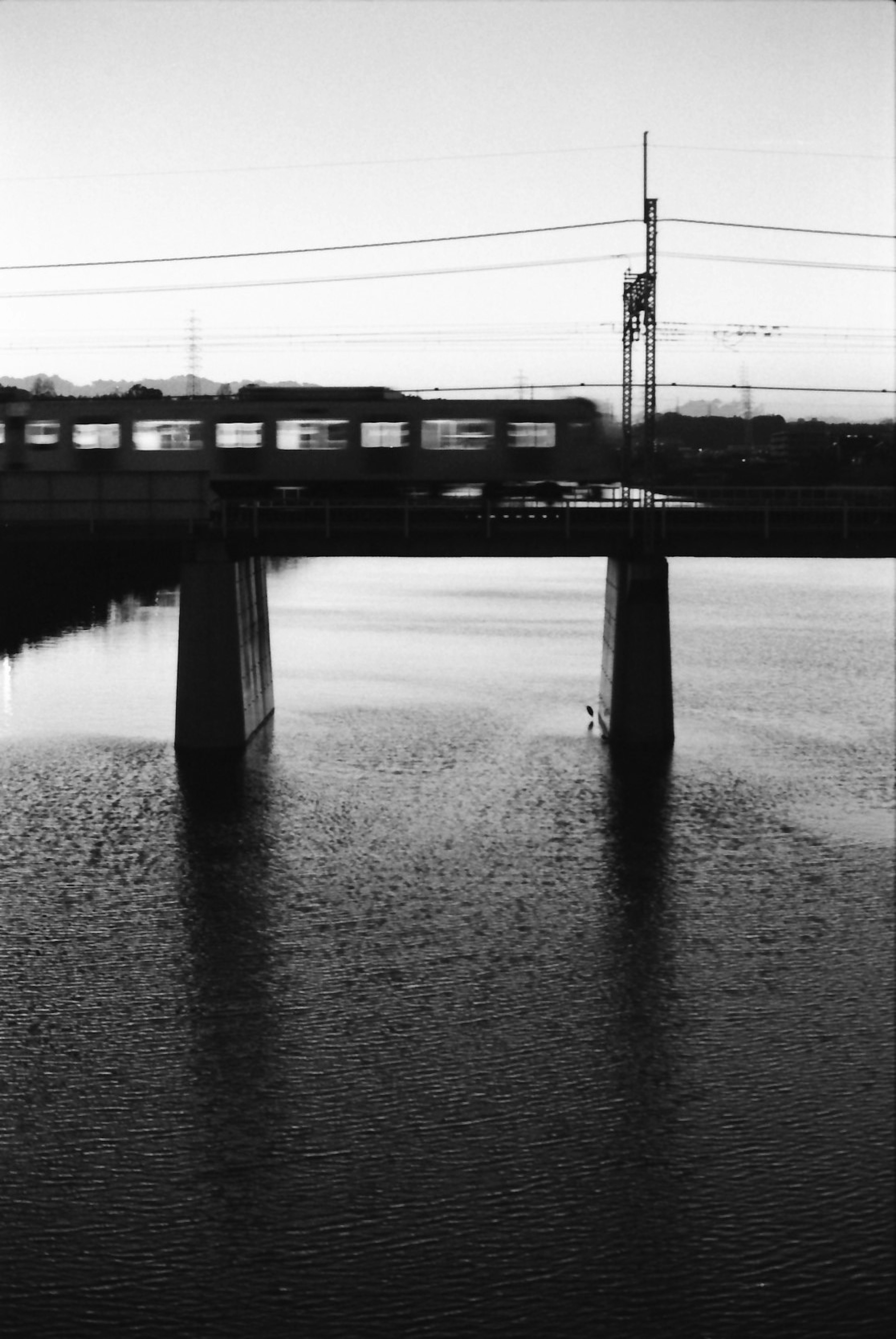 Ein Zug überquert eine Brücke in der Dämmerung mit Reflexionen im Wasser