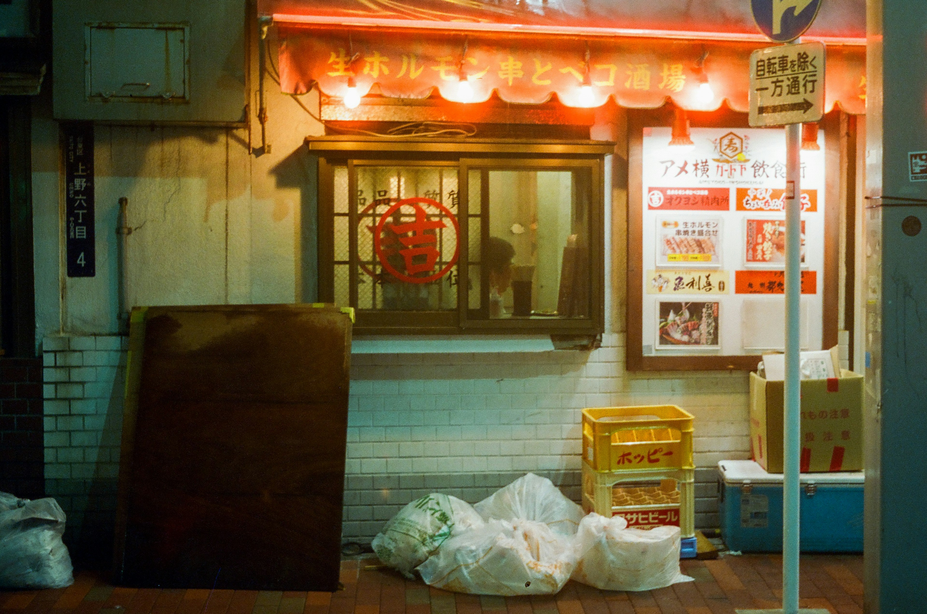 Vista de una calle débilmente iluminada con la ventana de un restaurante y basura esparcida