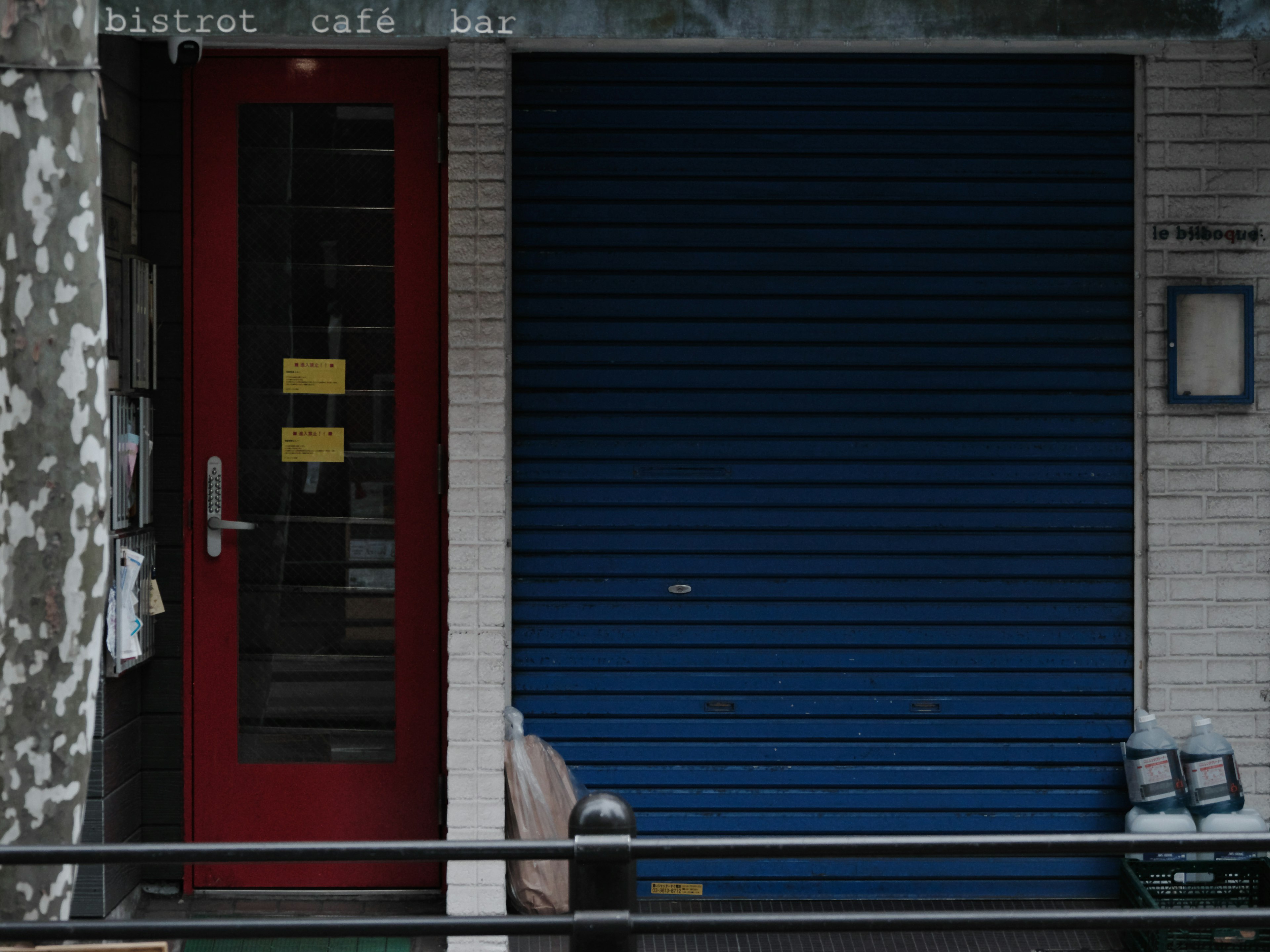 Cafe entrance with a red door and blue shutter